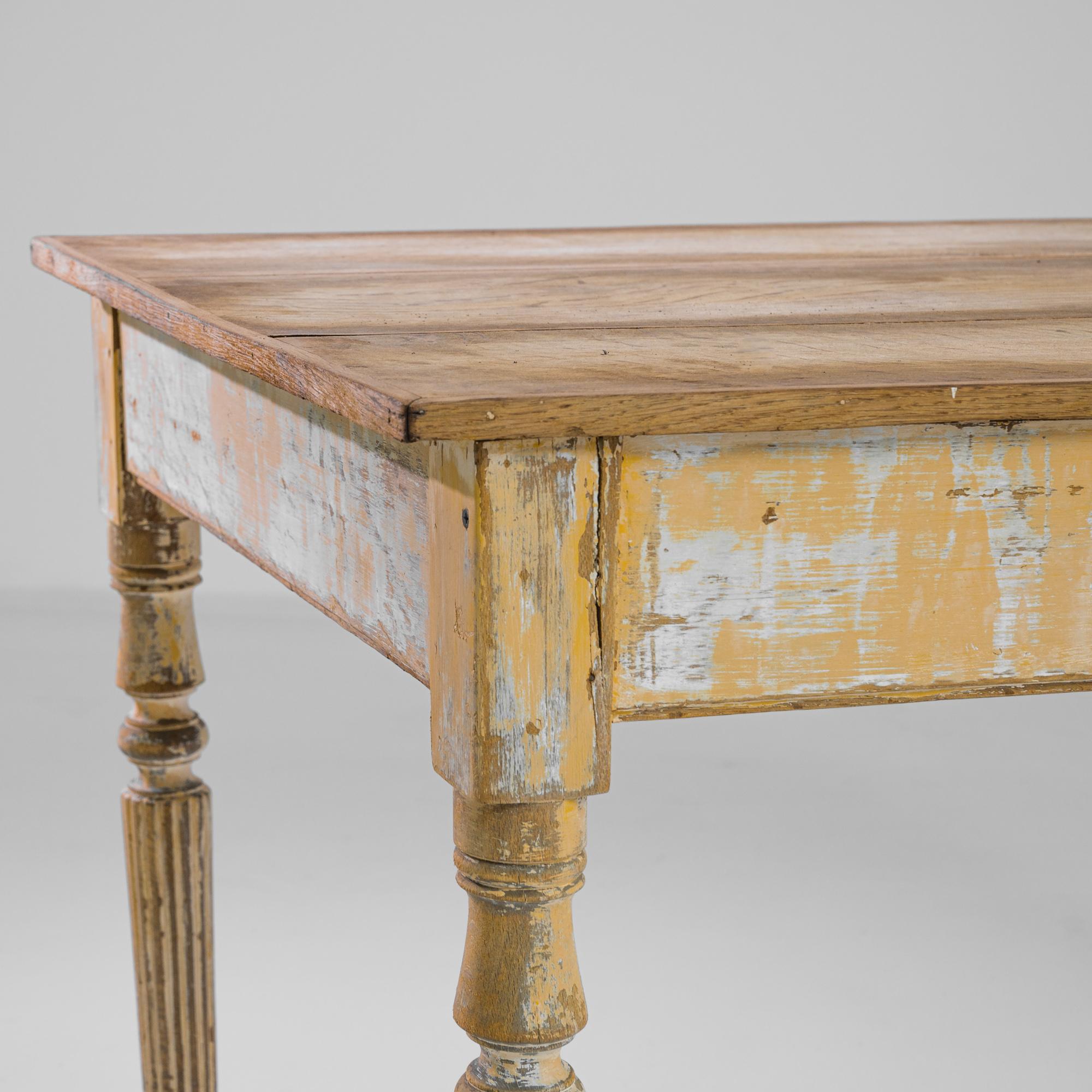 A wood patinated table from France, produced circa 1900. An antique occasional table with original yellow patination, featuring a sliding side drawer with engraved floral motif metal pull. Stood on four elegant banister style legs and stretching