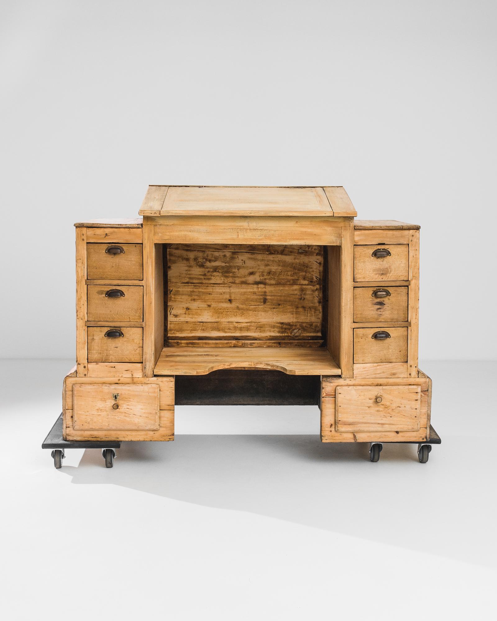 A wooden desk from France, produced circa 1880. A vintage writing desk perfect for the modern working person. Featuring a slanted writing surface with storage area inside, eight drawers in neat columns of four, footrest and podiums flanking the