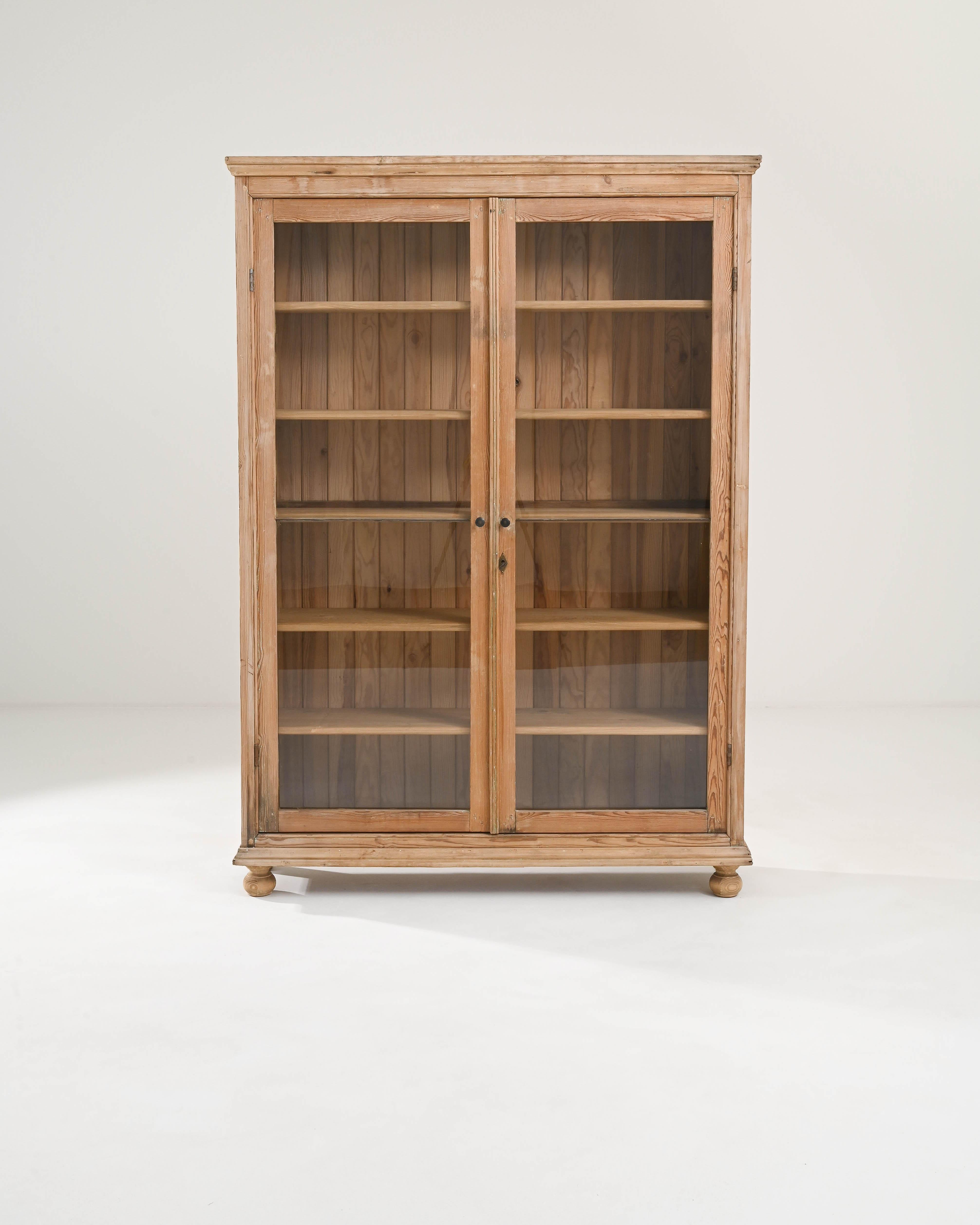 A wooden vitrine from France circa 1900. Rustic and brimming with simple geometric grace, this glass and wooden display case offers a cheery addition to any space. Two glass paned doors swing outwards to allow access to a spacious case with six