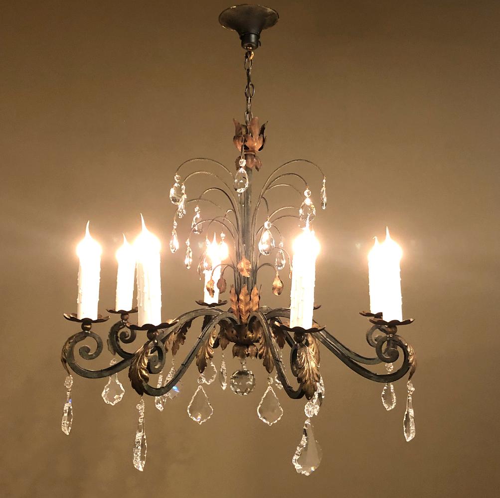 Antique Country French wrought iron and crystal chandelier is a splendid way to add charm, ambiance, and of course, lighting to any room! Surviving with its original canopy and a length of chain, it features eight hand-forged scrolled arms that are