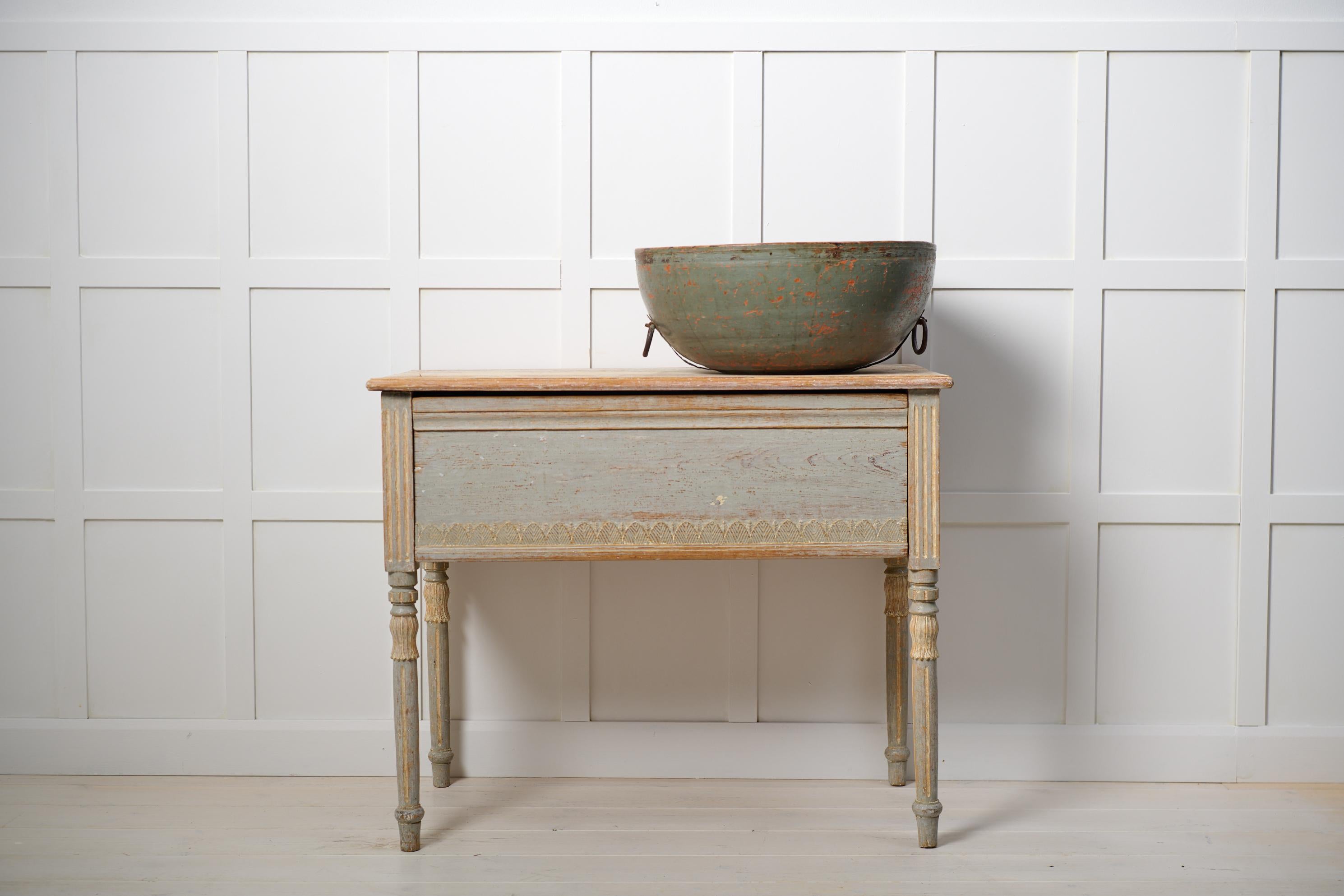 Antique country console table in gustavian style from northern Sweden. The table is made around 1820 and has original light paint with genuine patina and distress. Made by hand in solid pine. The table has round legs with carved wooden decor and the