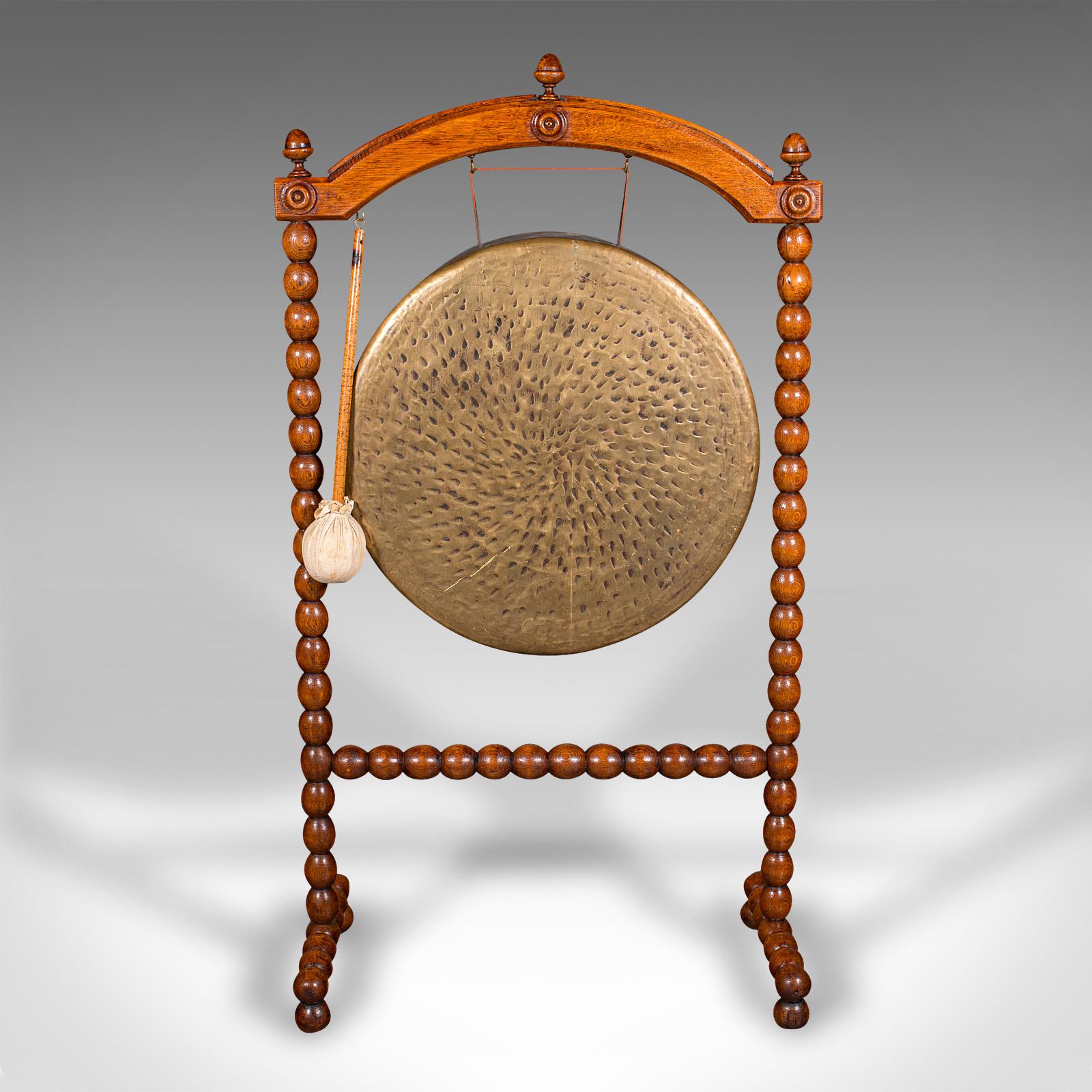 
This is an antique country house dinner gong. An English, bobbin turned oak chime frame, dating to the late Victorian period, circa 1890.

Fascinatingly decorative gong, with a pleasing tone
Displays a desirable aged patina and in good order