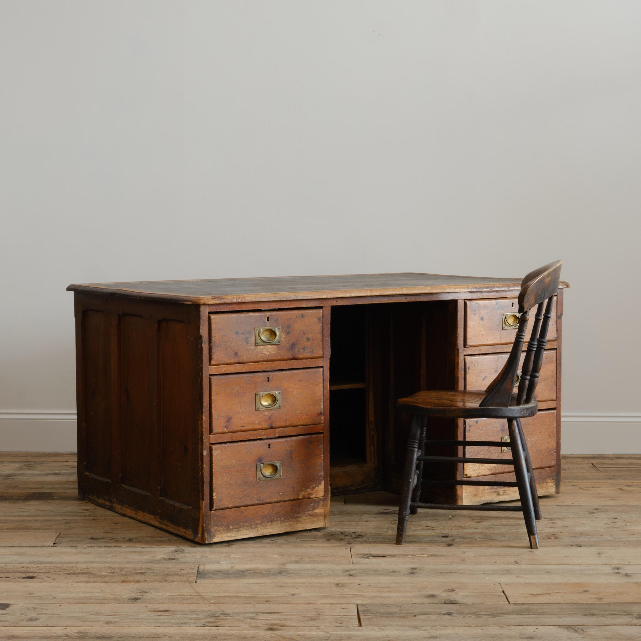 A large antique pine pedestal desk in antique country house condition from a large English country house. Raised on wooden casters and with a 2 door cupboard to the rear. The drawers with brass recessed handles. Panelled sides with stop chamfered
