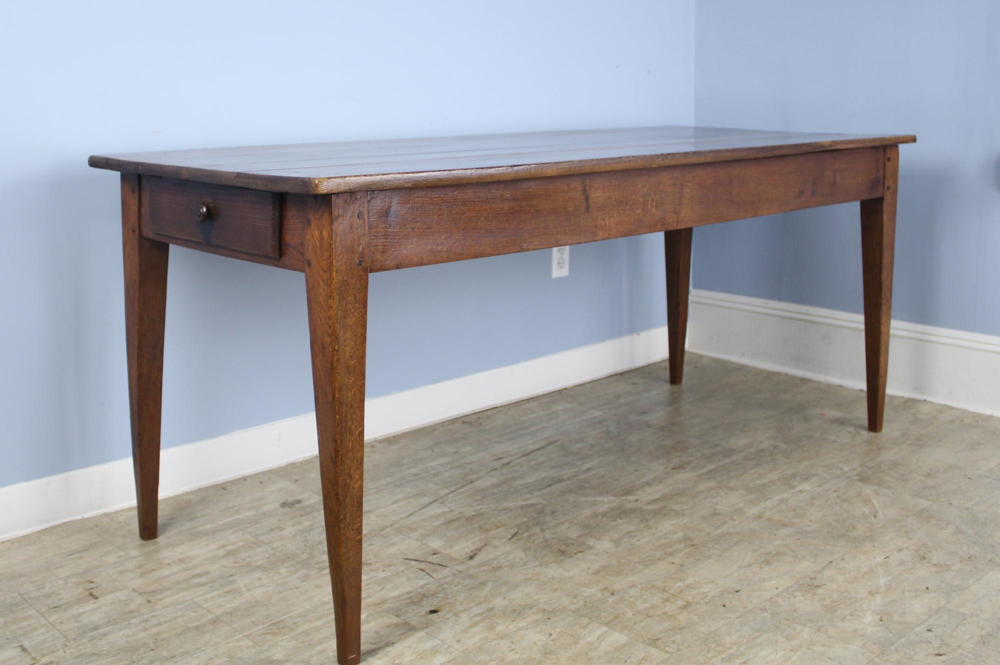 A good country oak farm table with classic tapered legs, pegged nicely at the apron. The top has a warm glowing patina with attractive grain. The apron height of 24 inches is good for knees and there are 62.5 inches between the legs on the long