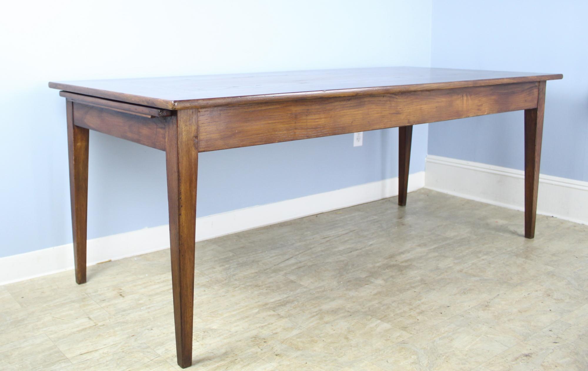 A fabulous clean simple, almost modern farm table in mellow oak. The top has lovely grain and interesting mitred corners, as well as a well preserved bread slide that is sturdy enough for side dishes or extra seating. With 71.25 inches between the