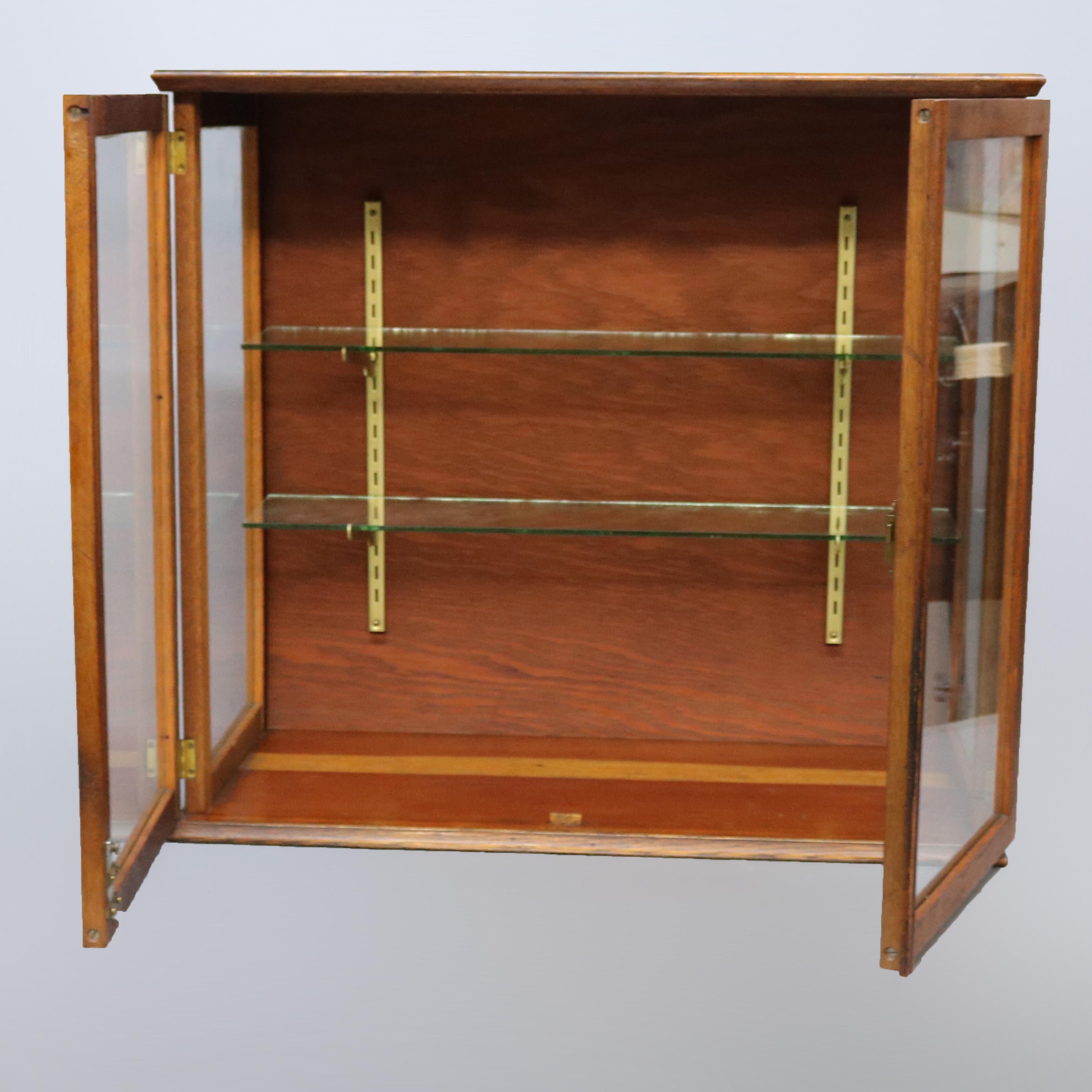 An antique country store counter top display cabinet offers oak construction with double glass doors opening to shelved interior, c1900

Measures: 28.75