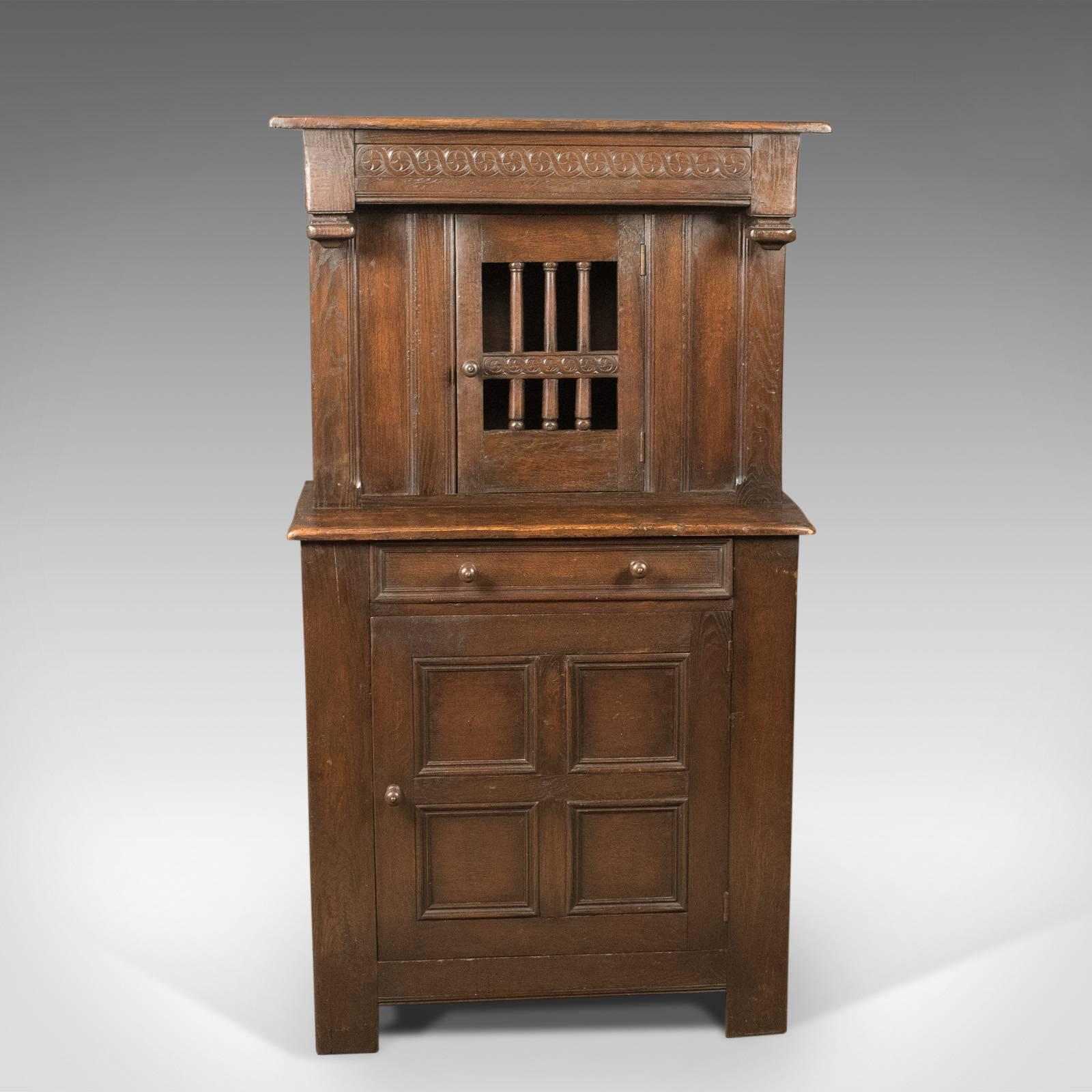 A handsome antique court cupboard crafted during the Edwardian period in the Elizabethan taste. English, oak and dating to circa 1910.

Presented in dark oak decorated with bands of reciprocating guilloché carving
Raised on extended stiles