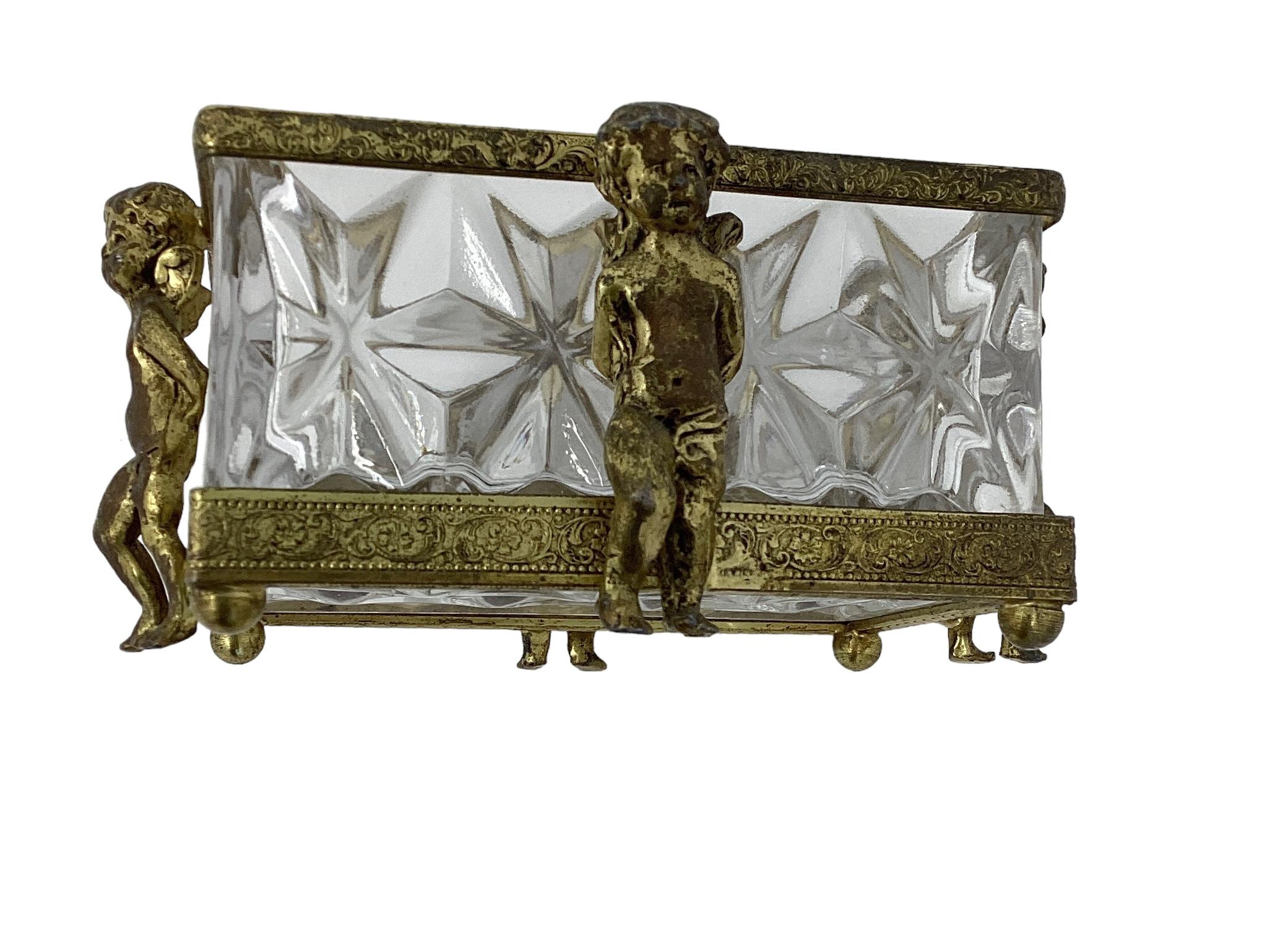 Antique Covered Crystal with Winged Bronze Puttis. The covered crystal box  with diamond shaped pattern sits in a bronze frame surrounded on four sides with putts. Wear and discoloration to putti.