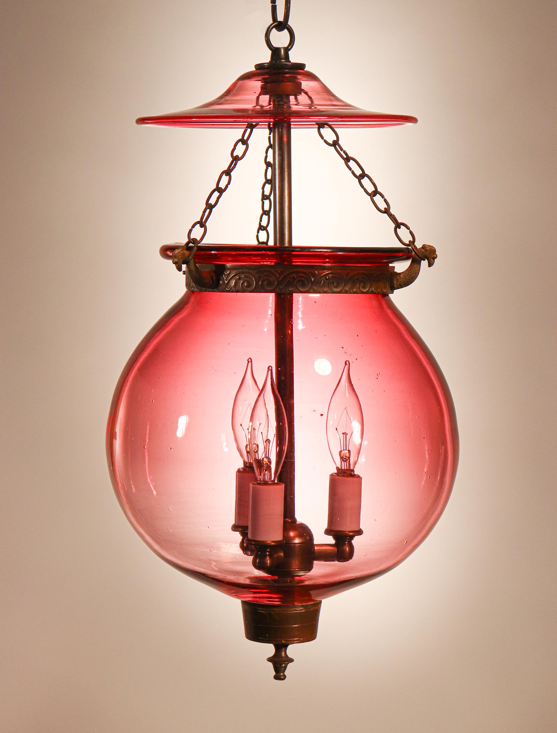 An exceptional lantern in our bell jar collection, this circa 1870 globe pendant has pleasing form and its cranberry hue casts a warm, comfortable light. The quality of the hand blown glass is very good, with desirable air bubbles and swirls in the