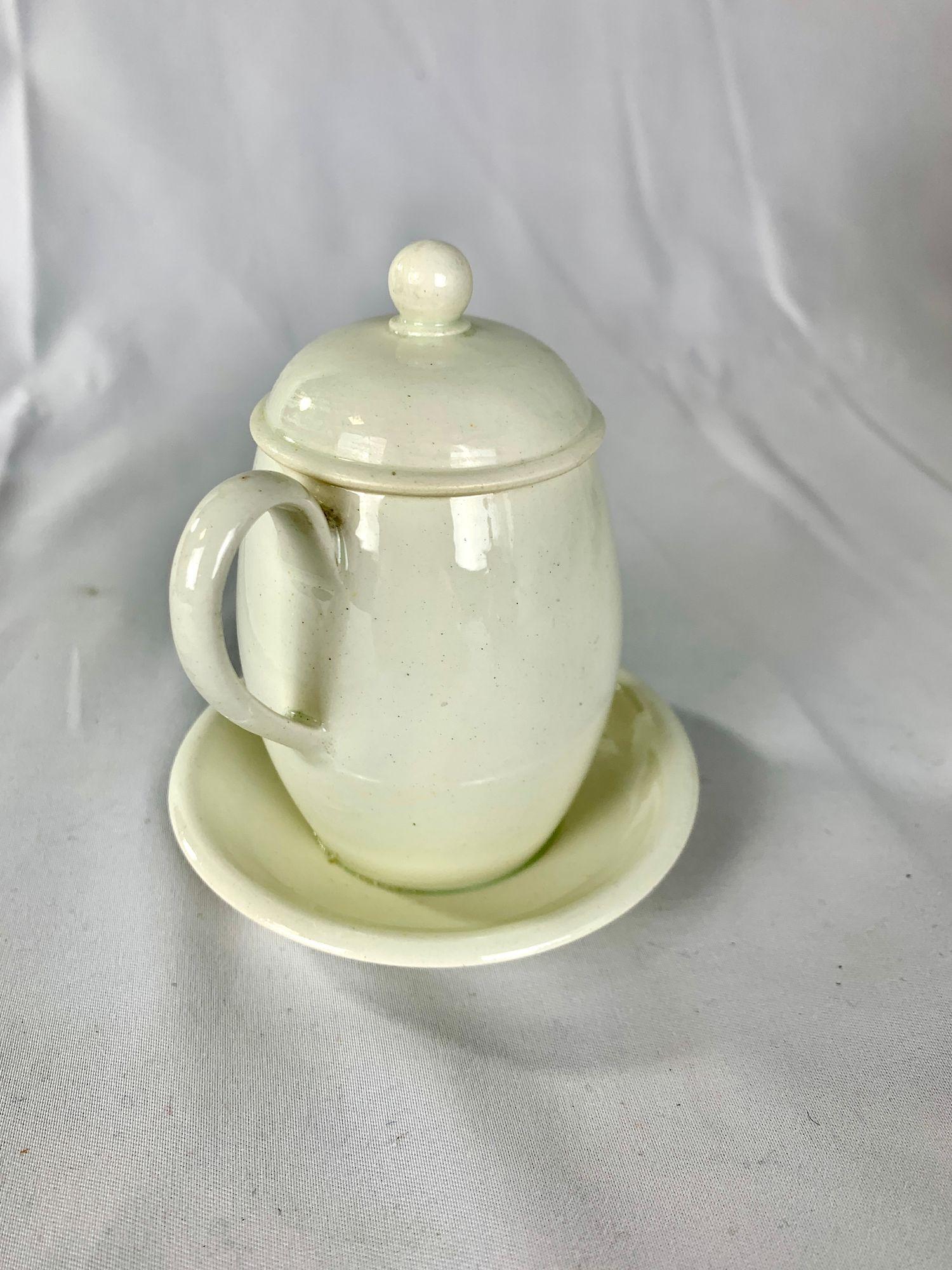 Questo antico vaso di senape in creamware è stato realizzato in Inghilterra intorno al 1810.
La pentola presenta un elegante corpo arrotondato a forma di barile con supporto integrato, un manico dalla forma aggraziata e un coperchio a cupola con un