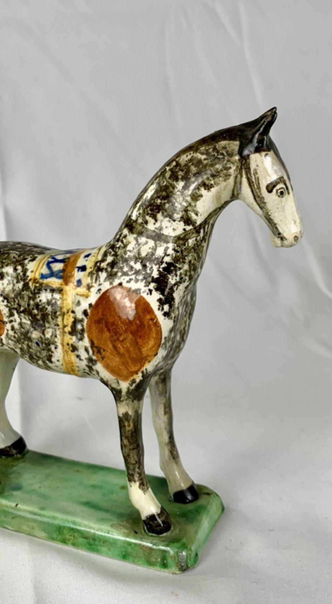 Raro caballo inglés de cerámica cremosa de principios del siglo XIX, fabricado en St. Anthony's Pottery, hacia 1800.
Esta encantadora figura está pintada a mano en gris moteado y negro. Unas vivas manchas rojo anaranjadas flanquean una silla de