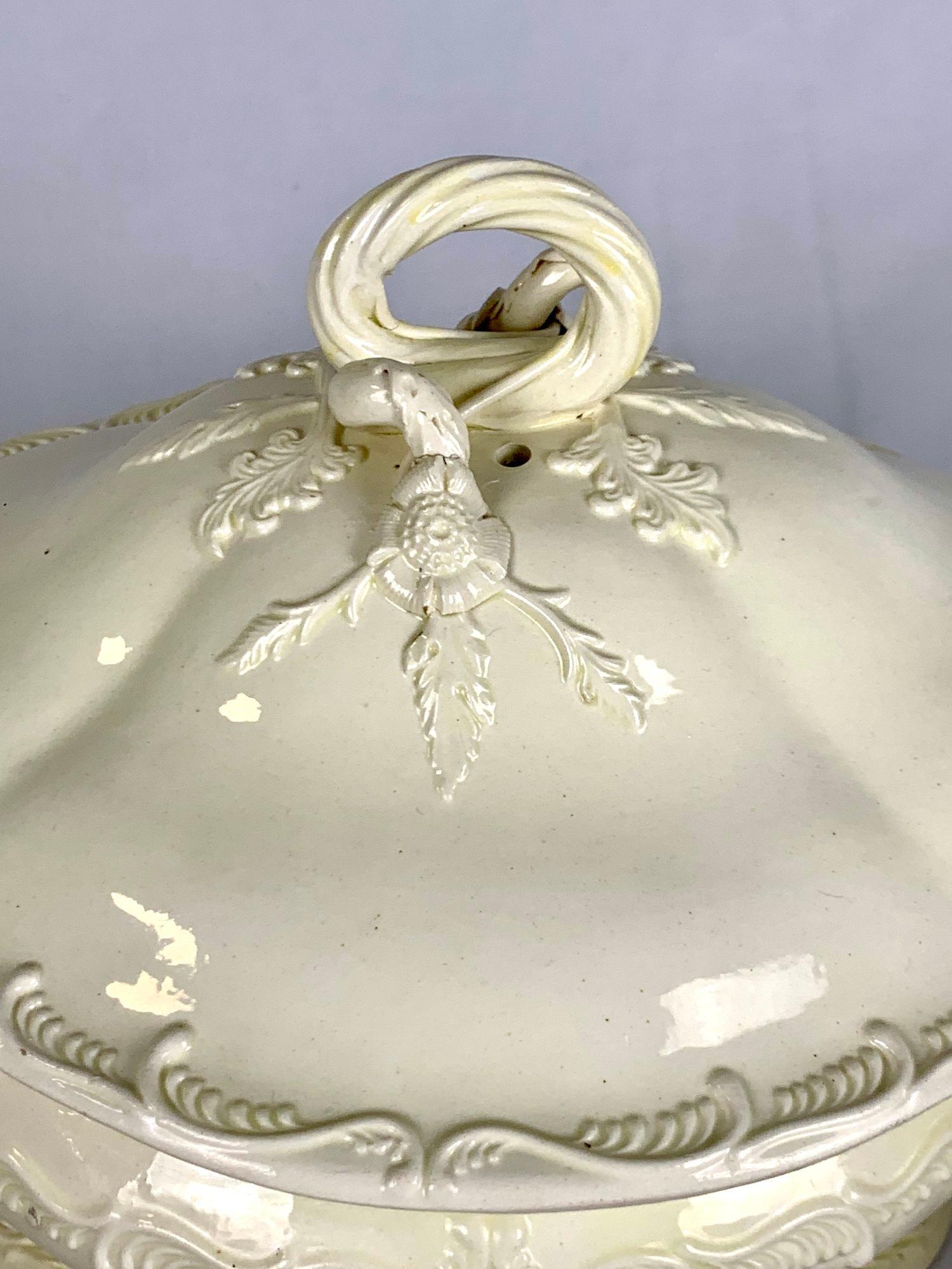 This elegant 18th-century English creamware tureen features beautifully molded foliate scrollwork and twisted rope handles. Featuring a domed lid with a decorative finial, this piece showcases the refined craftsmanship of Leeds Pottery. A beautiful