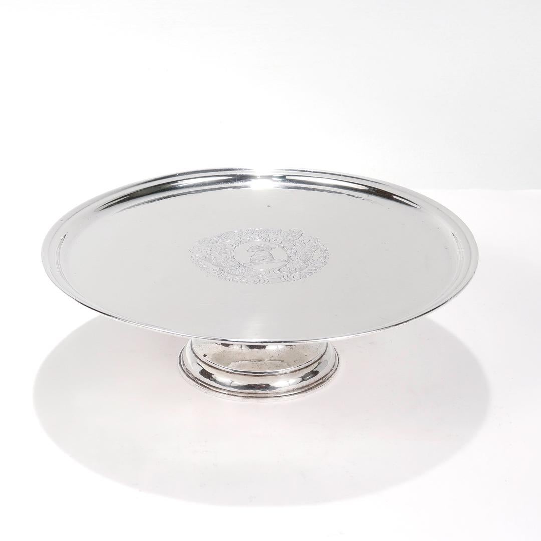 Un support à tazza ou à gâteau en argent ancien.

En argent sterling martelé à la main.

Par les frères Crichton (1890 - 1938).

Le centre est décoré d'un écusson familial ou d'armoiries gravées, avec un bélier au centre, entouré de motifs floraux,