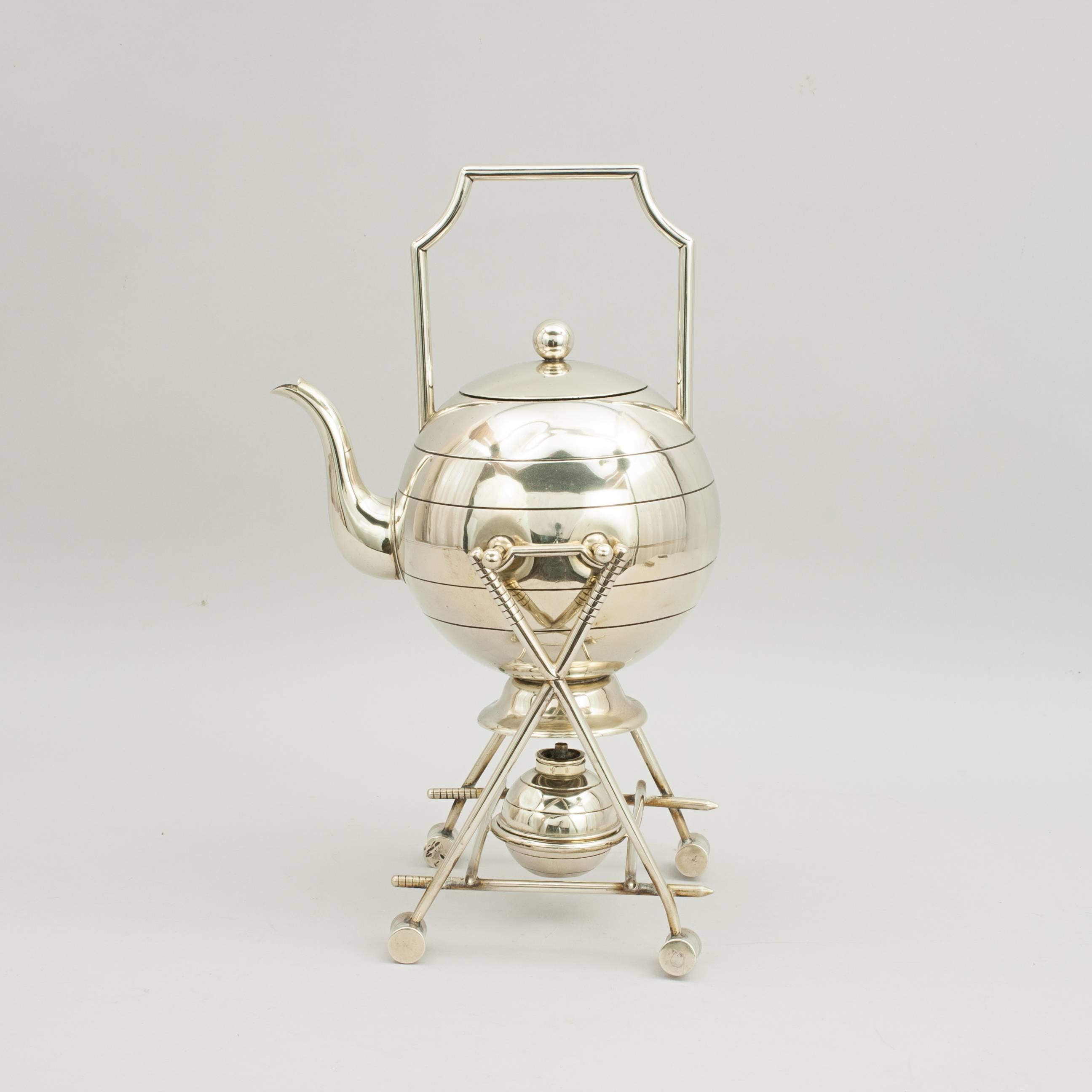 An English silver plated croquet tea pot with spirit warmer on stand. The pot stand is formed by two pairs of crossed croquet mallets, the teapot is designed as a croquet ball, a hoop forms the handle. A wonderful unusual spirit kettle that pivots