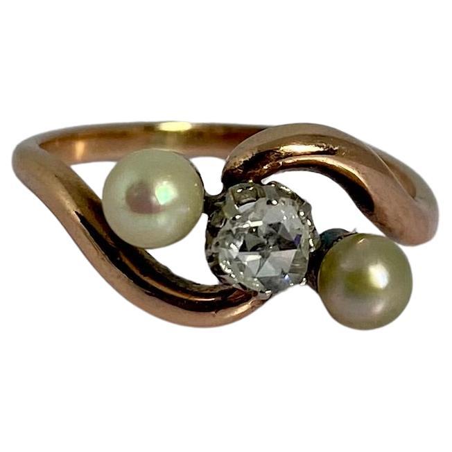 Experimenta la elegancia atemporal de este Anillo Cruzado de Oro Rosa de 18 quilates con Diamante Natural talla Rosa y Perlas de Agua Salada de principios del siglo XX. Meticulosamente elaborado en lujoso oro rosa de 18 quilates con intrincados
