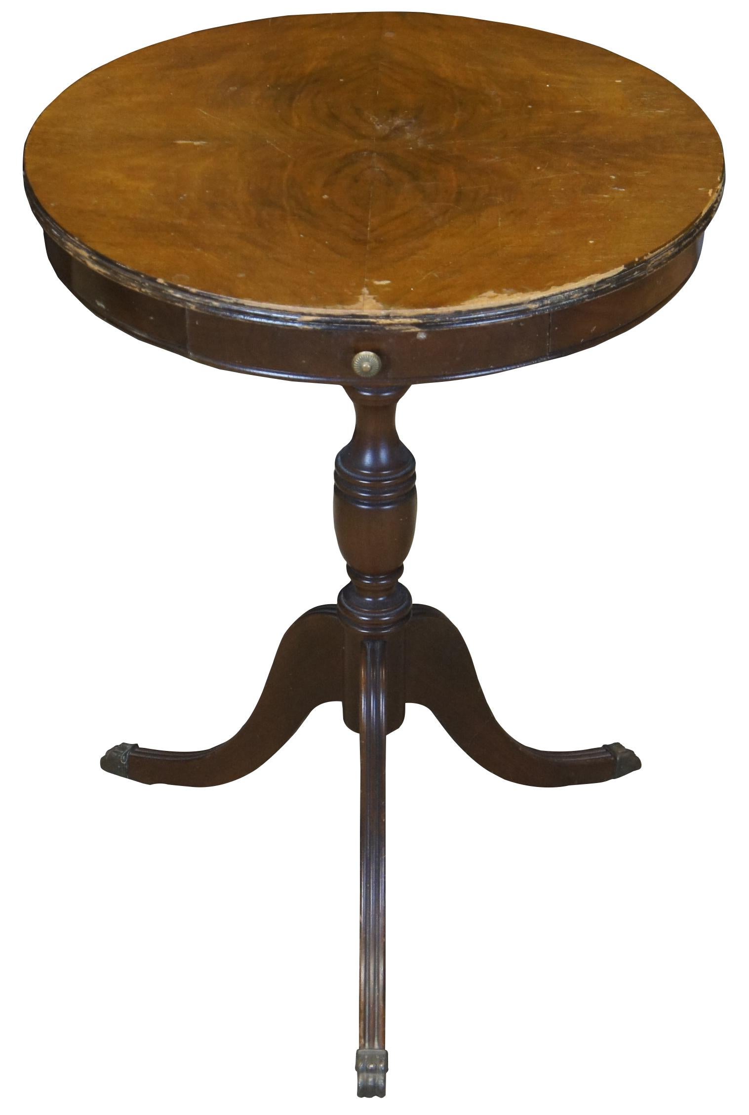 Antique mahogany side pedestal table. Duncan Phyfe styling featuring a round crotch mahogany top with small drawer, turned column and tripod base with fluting and brass capped feat. Measure: 27