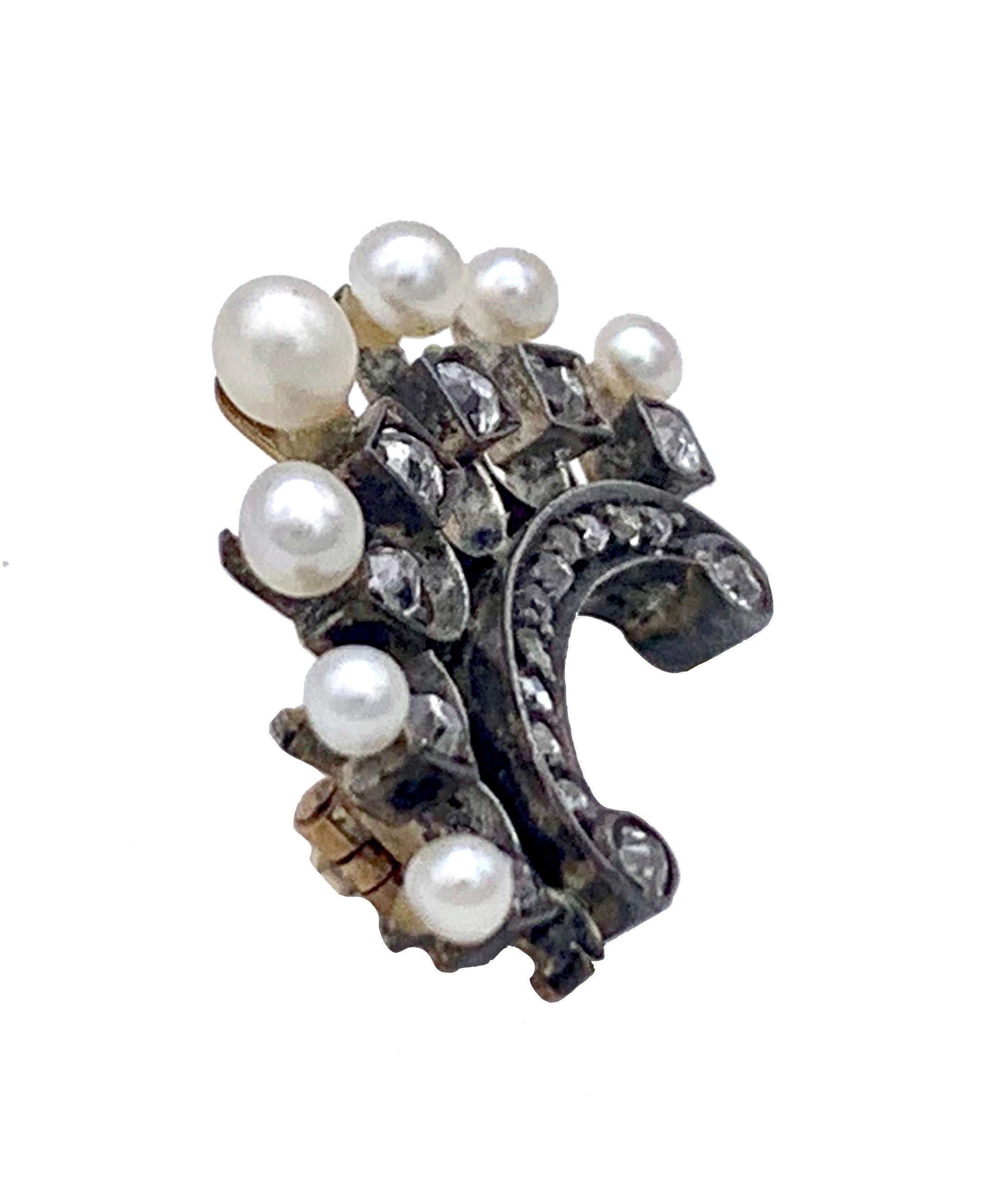 This charming little brooch is designed as a crown with seven prongs. Seven pearls, one larger oval pearl and six smaller round pearls represents the prongs of the crown. Each pearl is followed by a square mount with a diamond in the centre. A 