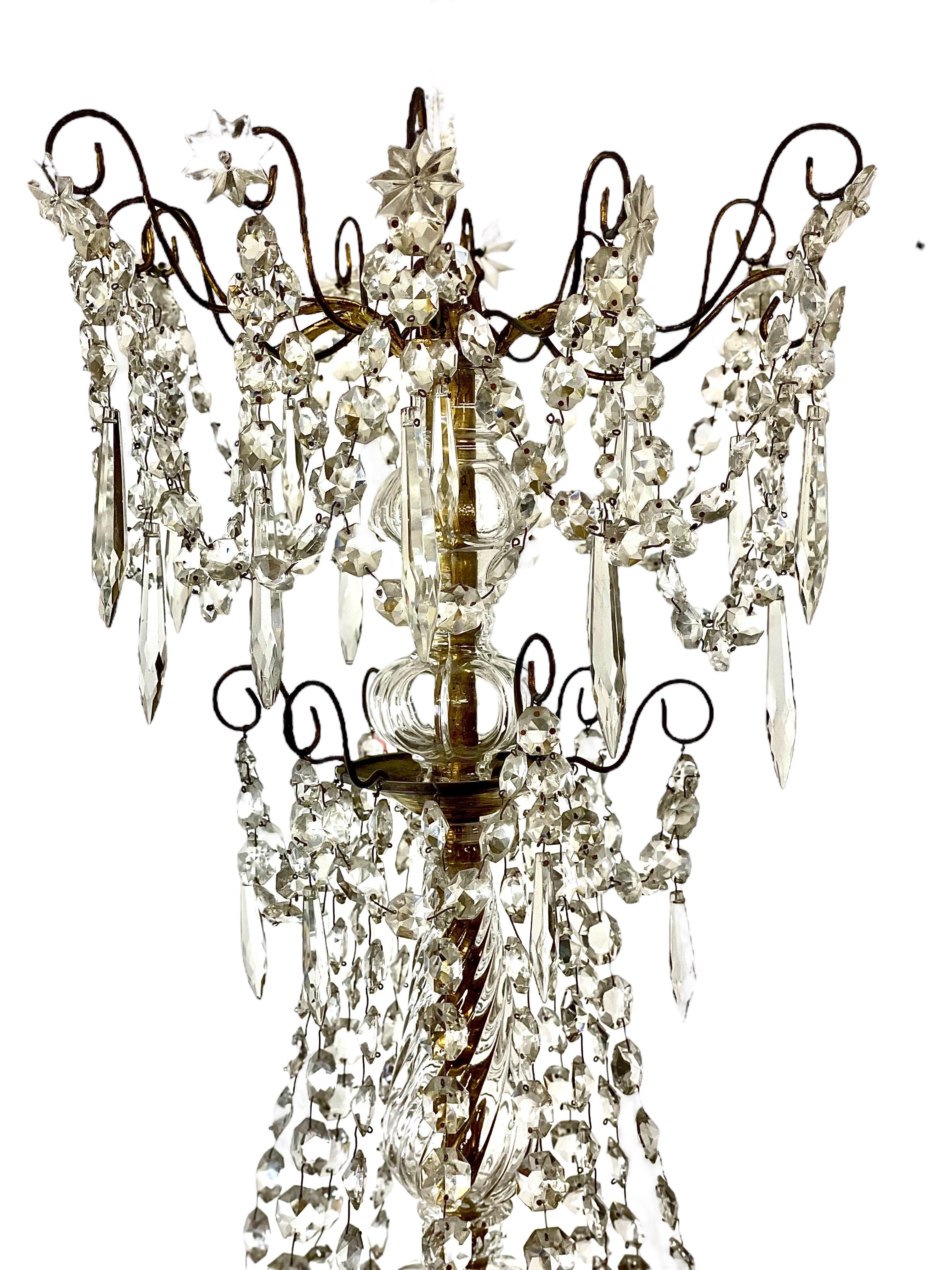 A glittering gilt brass, bronze and cut crystal tiered chandelier of twelve lights, dating from the second half of the 19th century. This truly magnificent piece features a crisply cut central baluster stem, from which twelve delicately curved