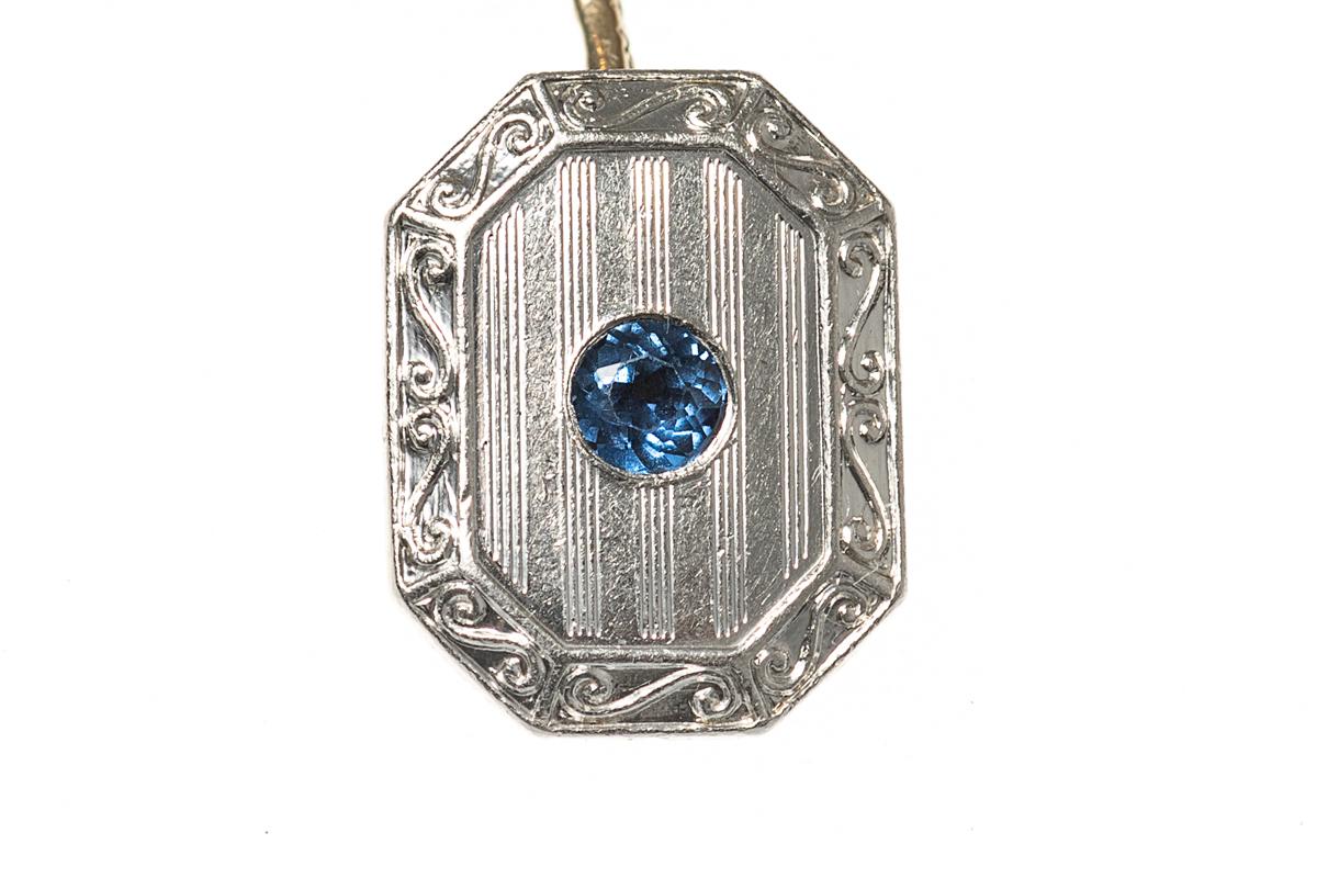 A heavy-weight pair of double sided cufflinks dating from the 1920’s, faced in 14 karat white gold with a facetted single sapphire centre. Rectangular in shape with cut corners and a raised border of a S-shaped scroll design. The reverse is in