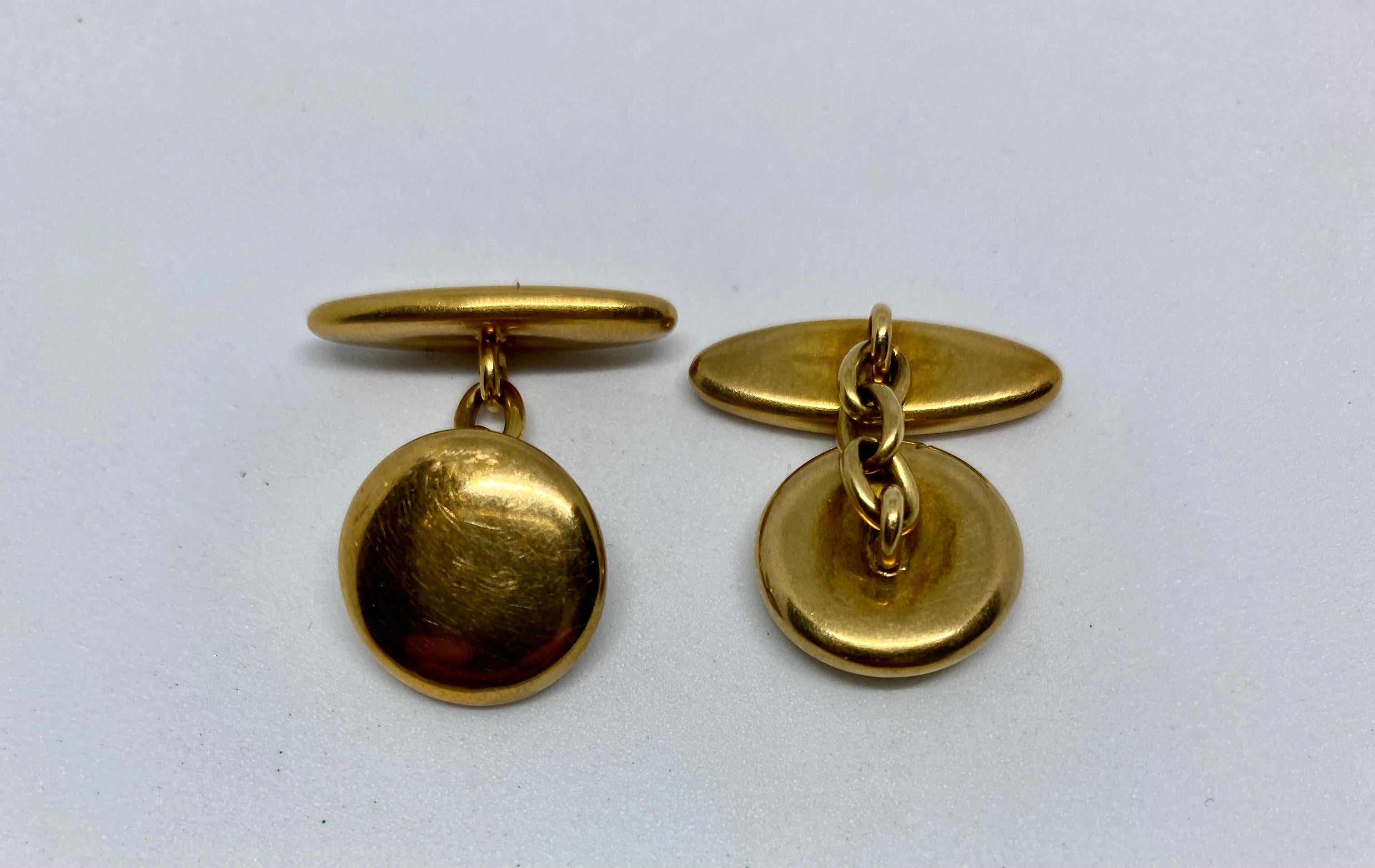 A simple, classic pair of antique cufflinks featuring round faces, oblong backs and chain connectors, all in solid, 14K yellow gold.

The cufflink faces measure 13.5mm in diameter; the oval backs measure 20mm by 6.8mm. Together the cufflinks weigh