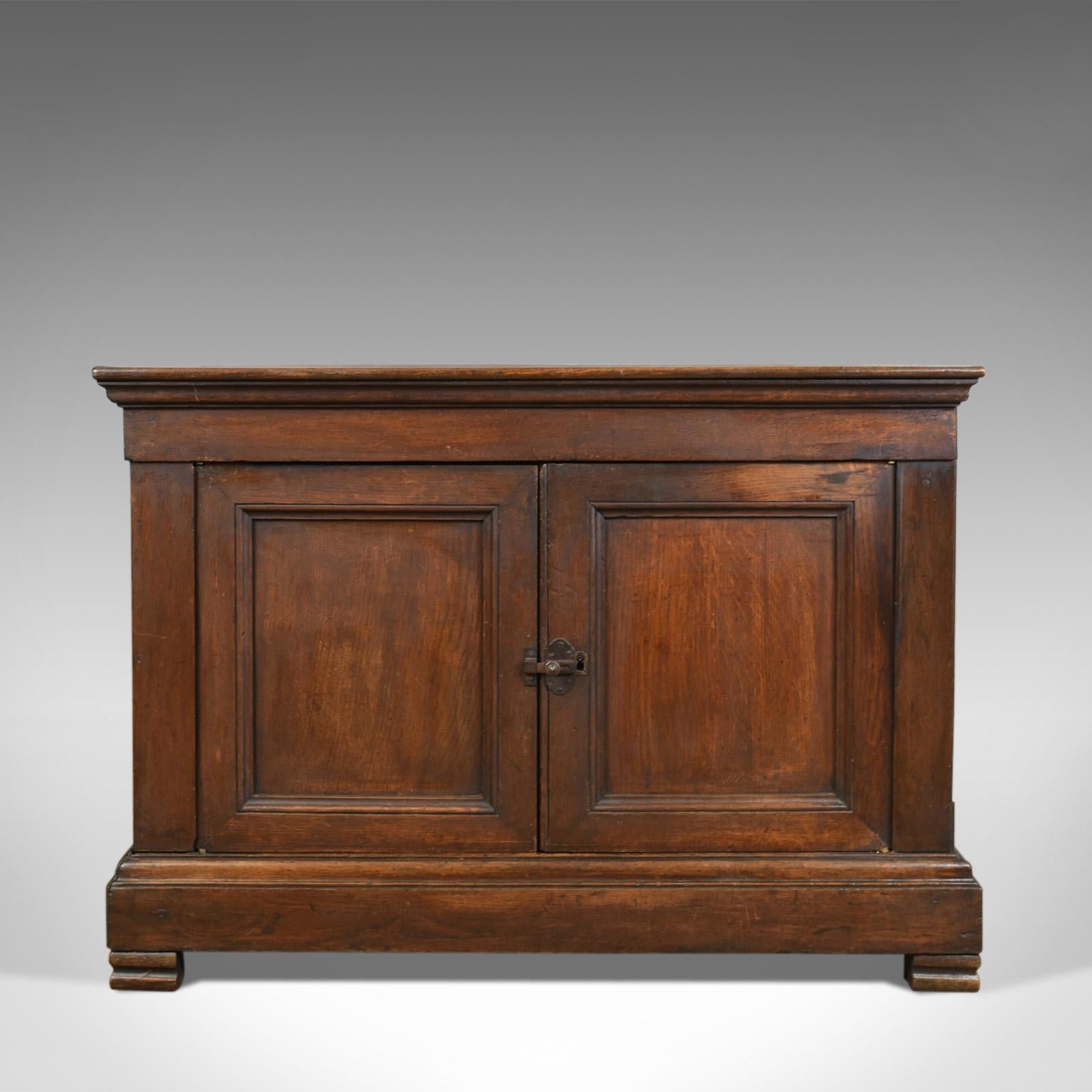 This is an antique cabinet, a 19th century, French, oak cabinet dating to circa 1850.

Attractive warm hues to the oak with an appealing aged patina
Plank top with attractive edge moulding detail
Continuous, broad plinth base raised on shaped