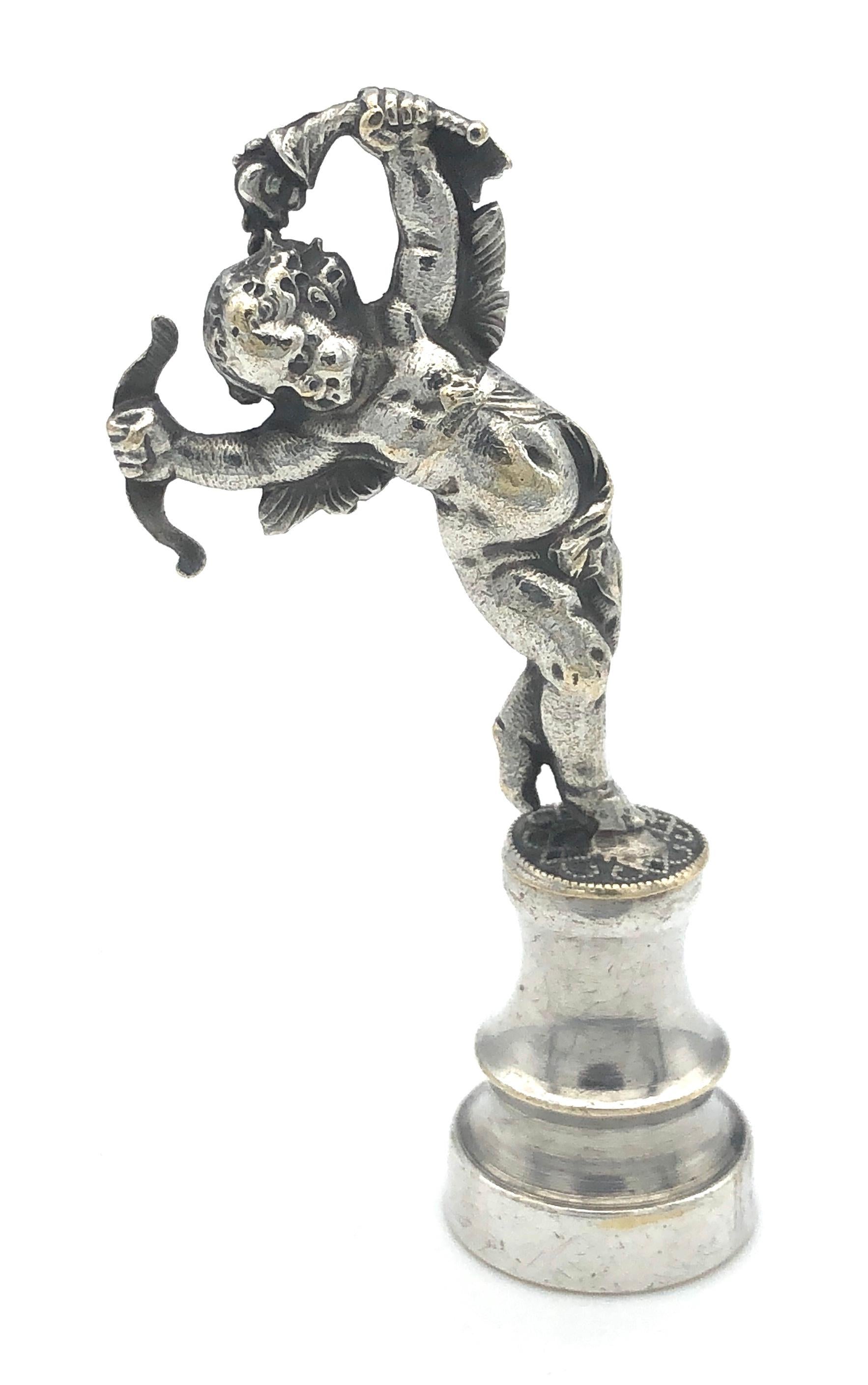 Delightfully modelled cupid holding bow and arrows in his hands. The dancing amor is standing on a pedestal. The seal is made out of silver plated metal and carries the initials J D. This charming figure was most certainly offerred as a love token.
