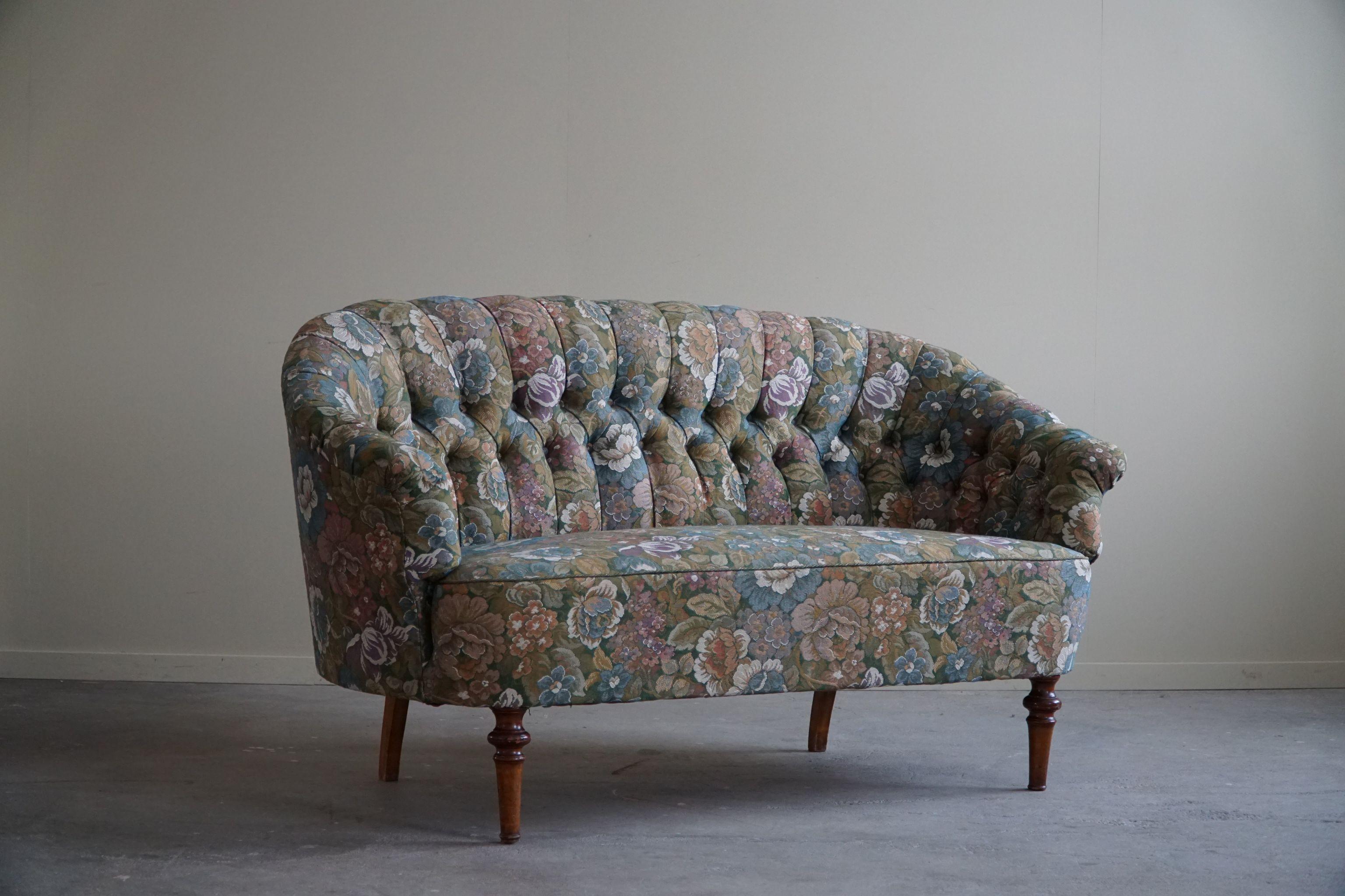 This antique sofa, skillfully crafted by a skilled Danish cabinetmaker in the early 1900s, stands as an exemplar of timeless elegance and expert craftsmanship. The upholstery, adorned with a flora fabric in great condition that adds a touch of
