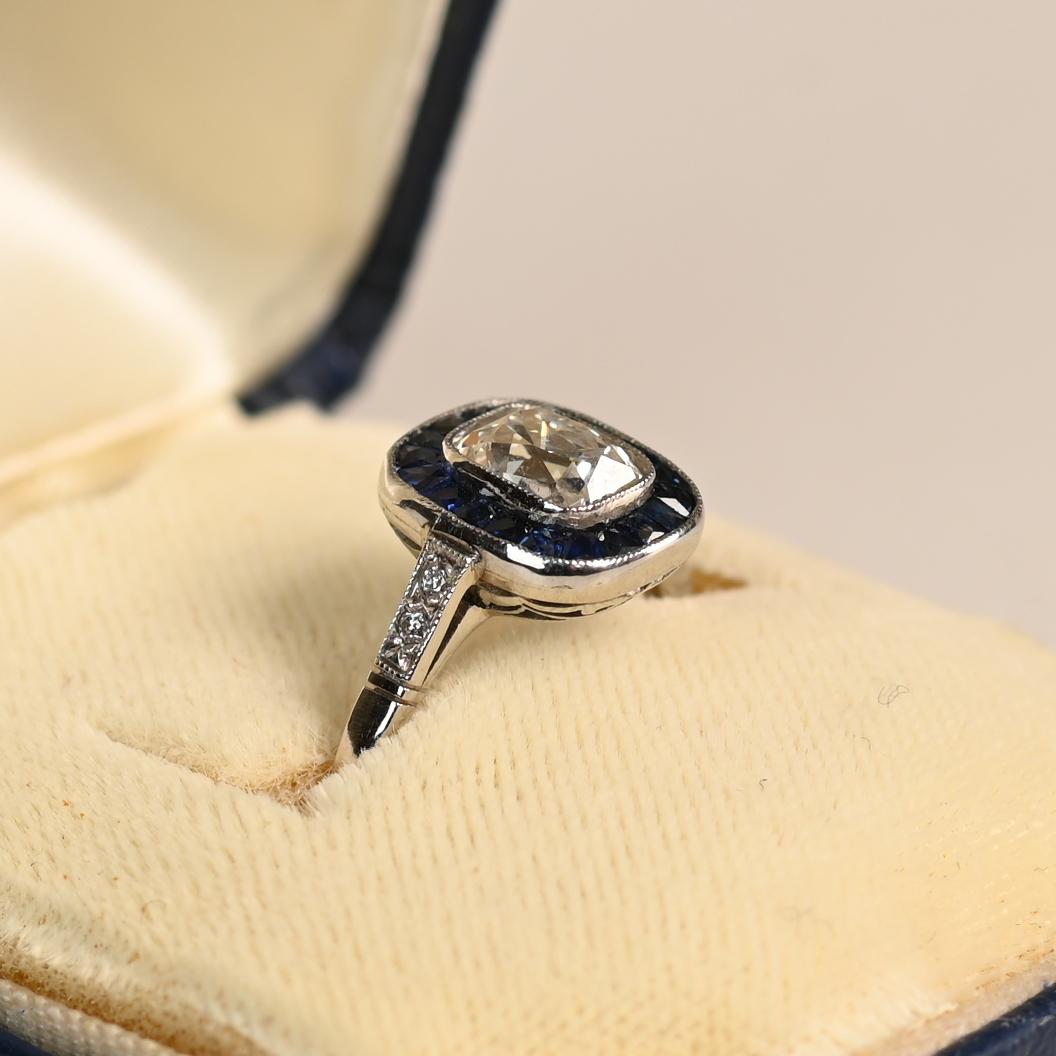 Questo squisito anello di fidanzamento con aureola presenta un diamante antico dal taglio a cuscino allungato mozzafiato, del peso di circa 1,00 carati. Con una gradazione di colore J e una purezza VS2, la pietra centrale irradia eleganza e