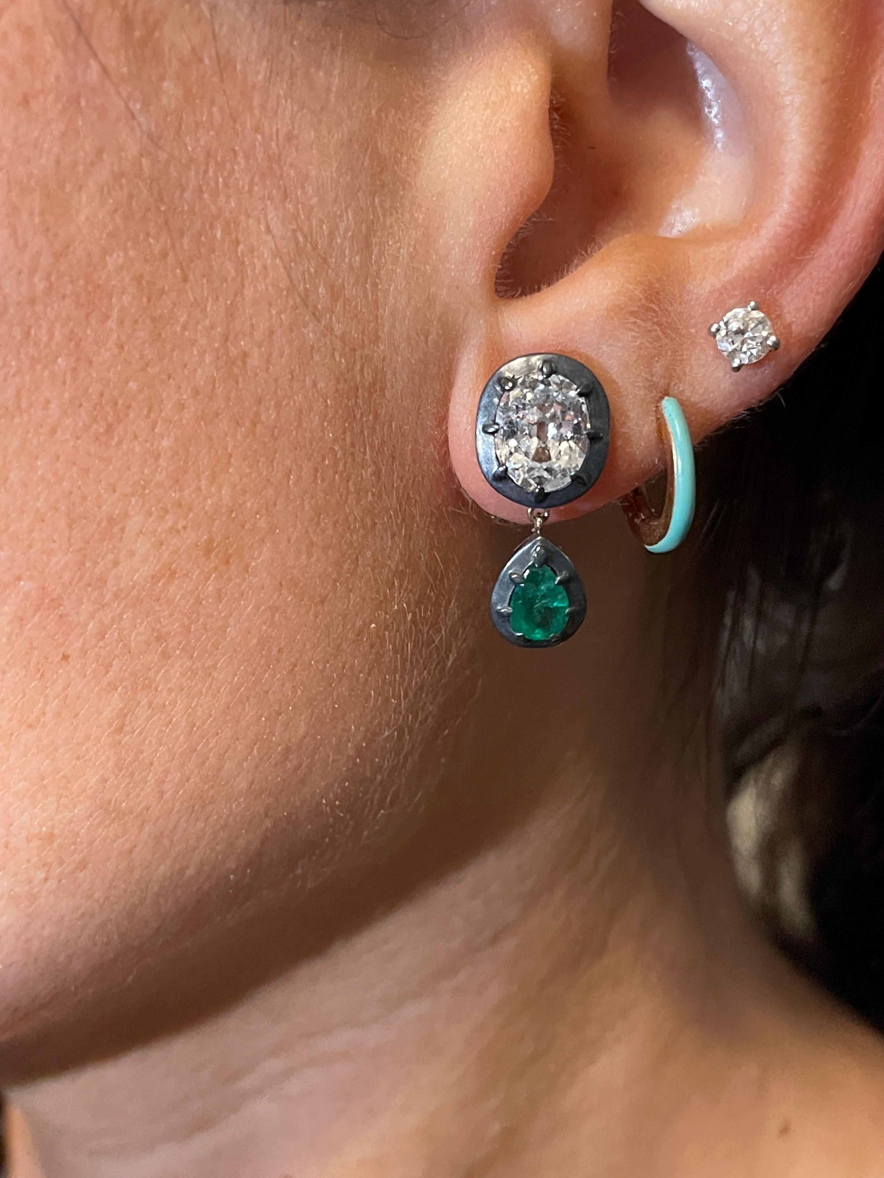 Georgian-era style characteristics with contemporary design, as is modelled perfectly by these beautiful pair of 1,15 and 1,05 cts Old Cushion Cut Diamonds of G-H color.
 Each cushion has a Vibrant green emerald drop hanging.
They’re handcrafted in