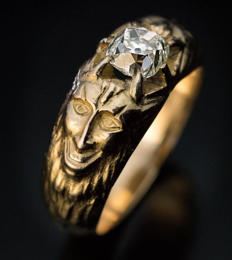Circa 1900

This highly unusual one-of-a-kind antique 14K gold ring is centered with a bright white (G color, VS2 clarity) old cushion cut diamond (1.14 ct) flanked by two satyr masks cast in high relief. The diamond measures 5.72 x 5.38 x 4.45