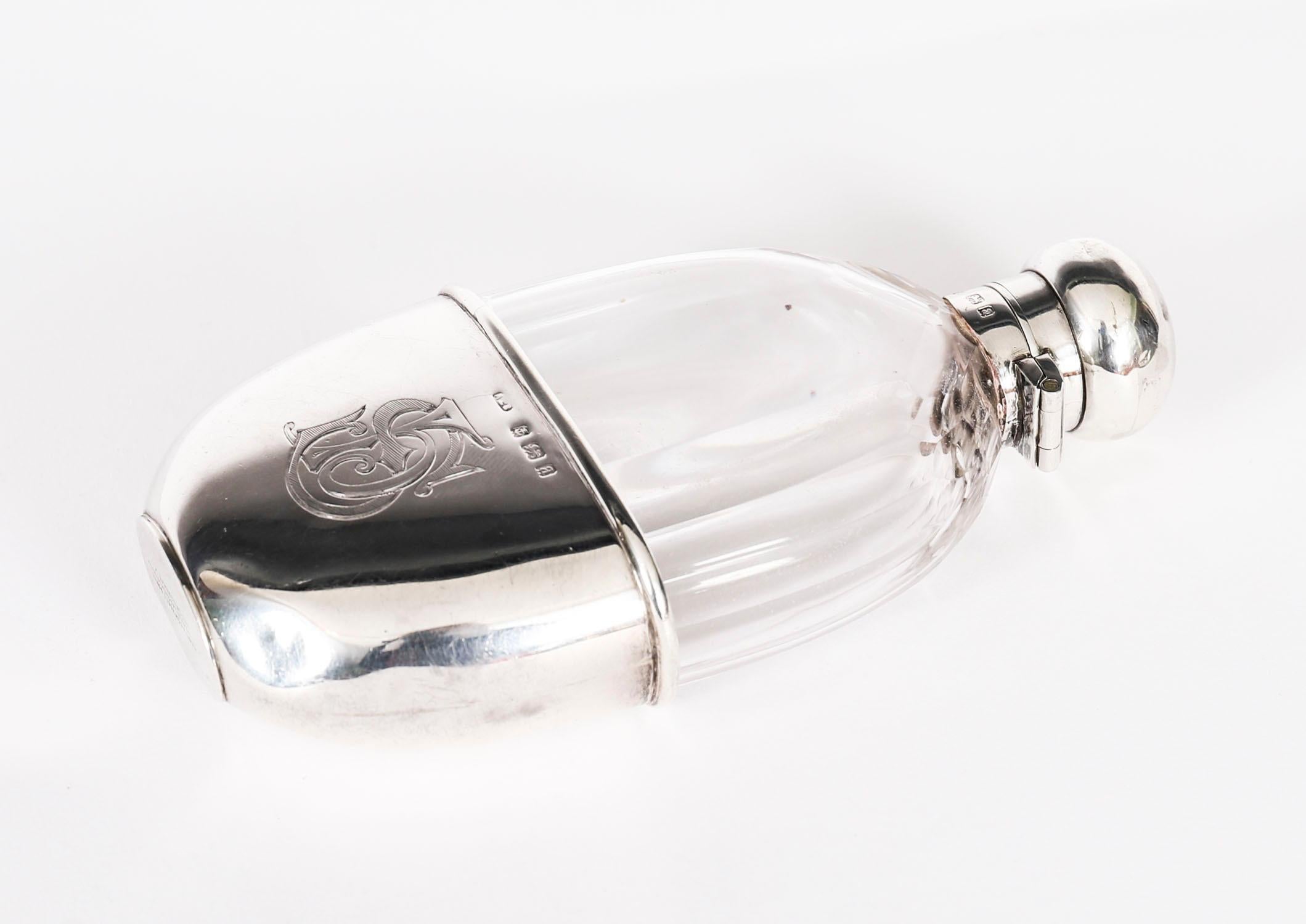 This elegant antique cut glass and sterling silver hip flask bears makers marks for the silversmith  Asprey & Co, England and the date mark for 1900.

It features a classic oval faceted glass form with a circular bayonet style screw down locking