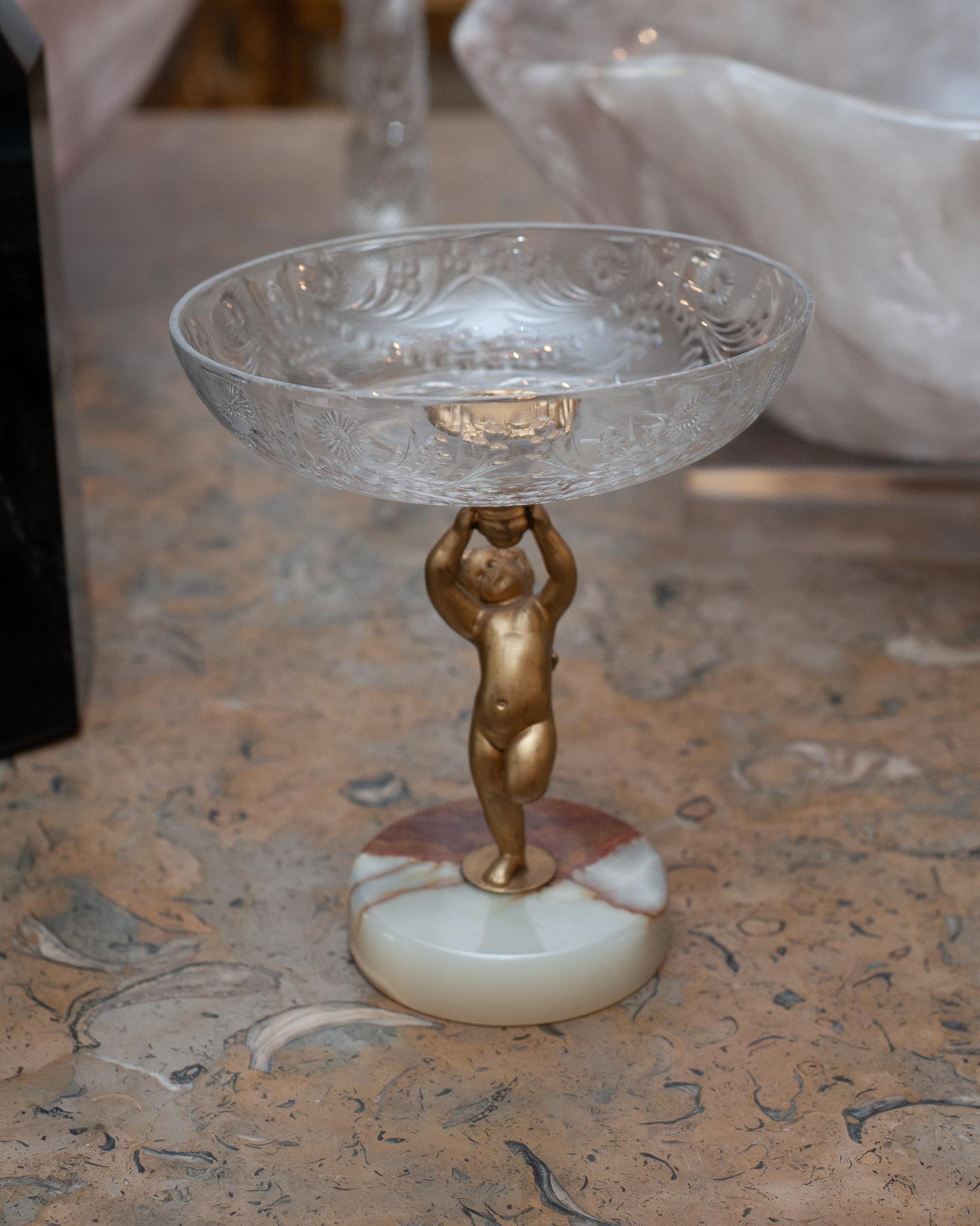 A beautiful small antique compote dish on an onyx marble base. The bowl is composed of cut crystal and is supported by a bronze cherub. Perfect for holding candies or nuts.