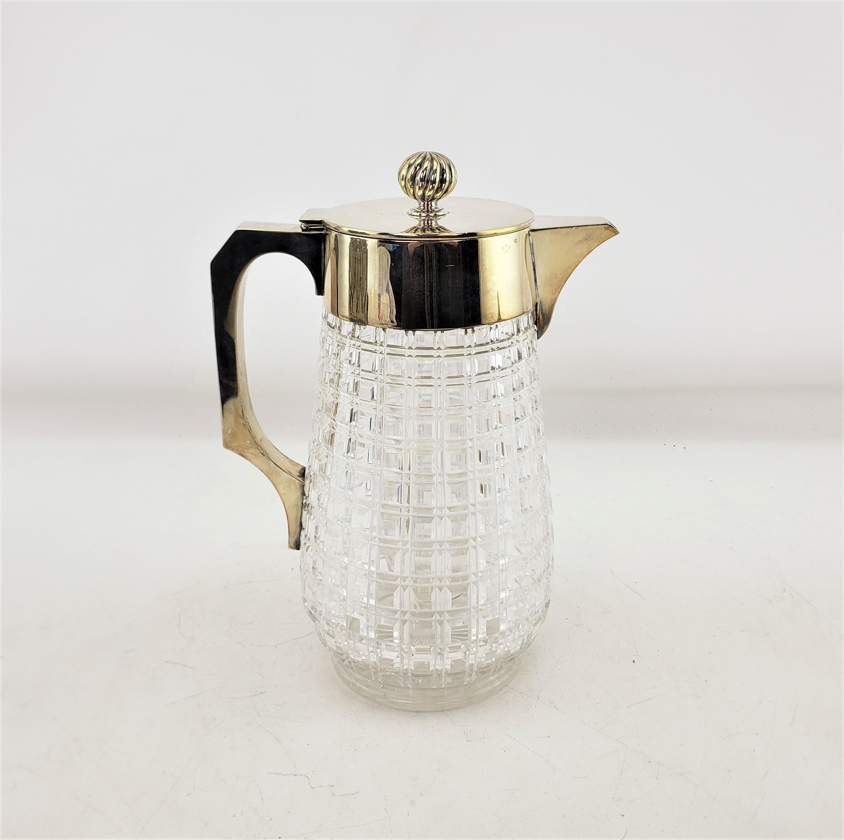 This antique claret jug is hallmarked by an unknown maker, and originated from England and dates toa apprximately 1920 and done in the period Art Deco style. The jug is composed of heavy faceted lead crystal with a well constructed handle and hinged