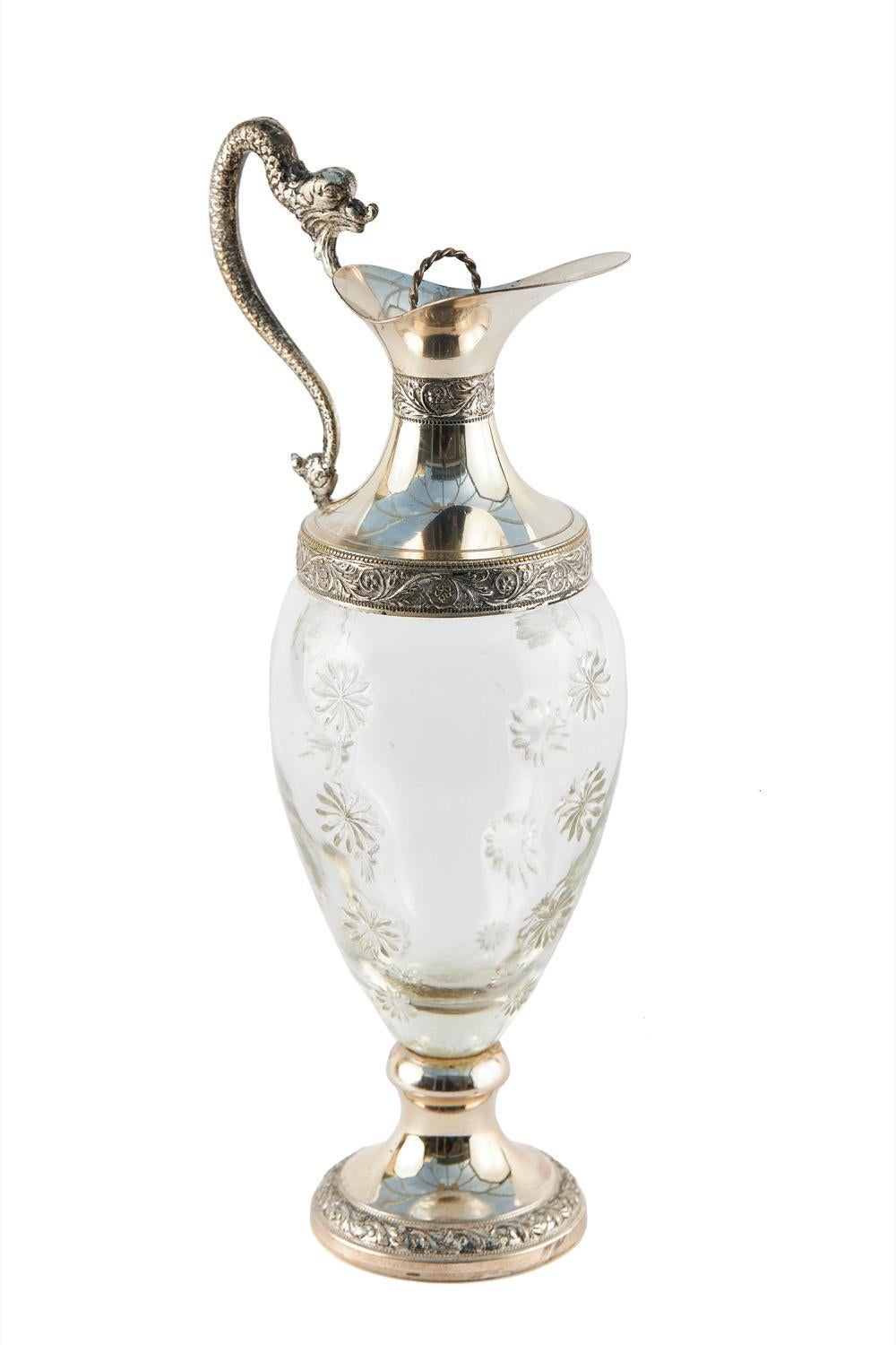 Antique Cut Glass And Silver Plated Claret Jug with a lift up lid and quality shaped ornate handle, bulbous shaped cut glass centre with flower decoration raised on an ornate silver plated circular base with engraving detail.