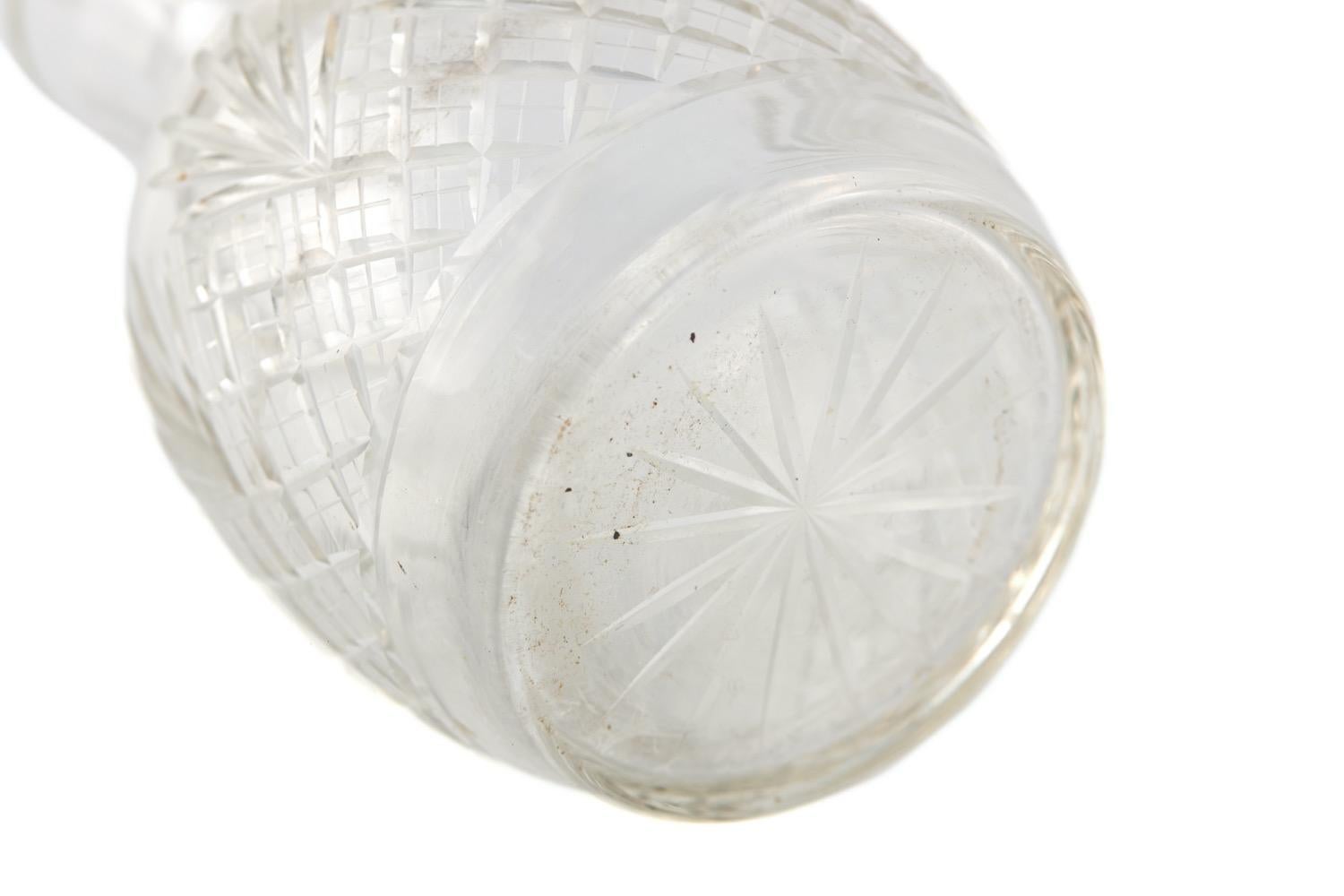 Cette carafe en verre taillé du 19e siècle est ouverte et présente un corps bulbeux avec une décoration en verre taillé en forme de diamant et d'étoile, ainsi qu'une décoration en forme d'étoile sur le dessous.