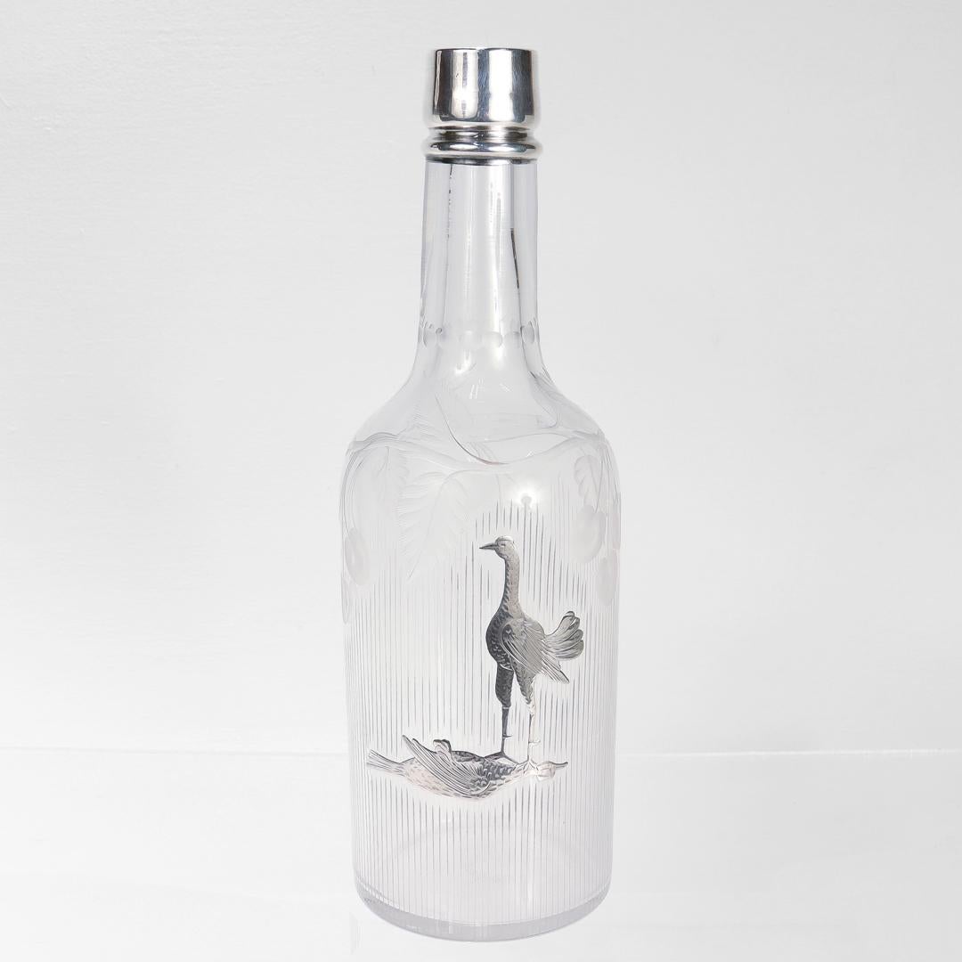 Botella o decantador antiguo de bar.

En vidrio soplado con recubrimiento de plata.

Con borde montado en plata y cuerpo grabado.

Decorado en el cuerpo con dos pájaros plateados (gallos de pelea o de caza) con un pájaro victorioso sobre el cuello