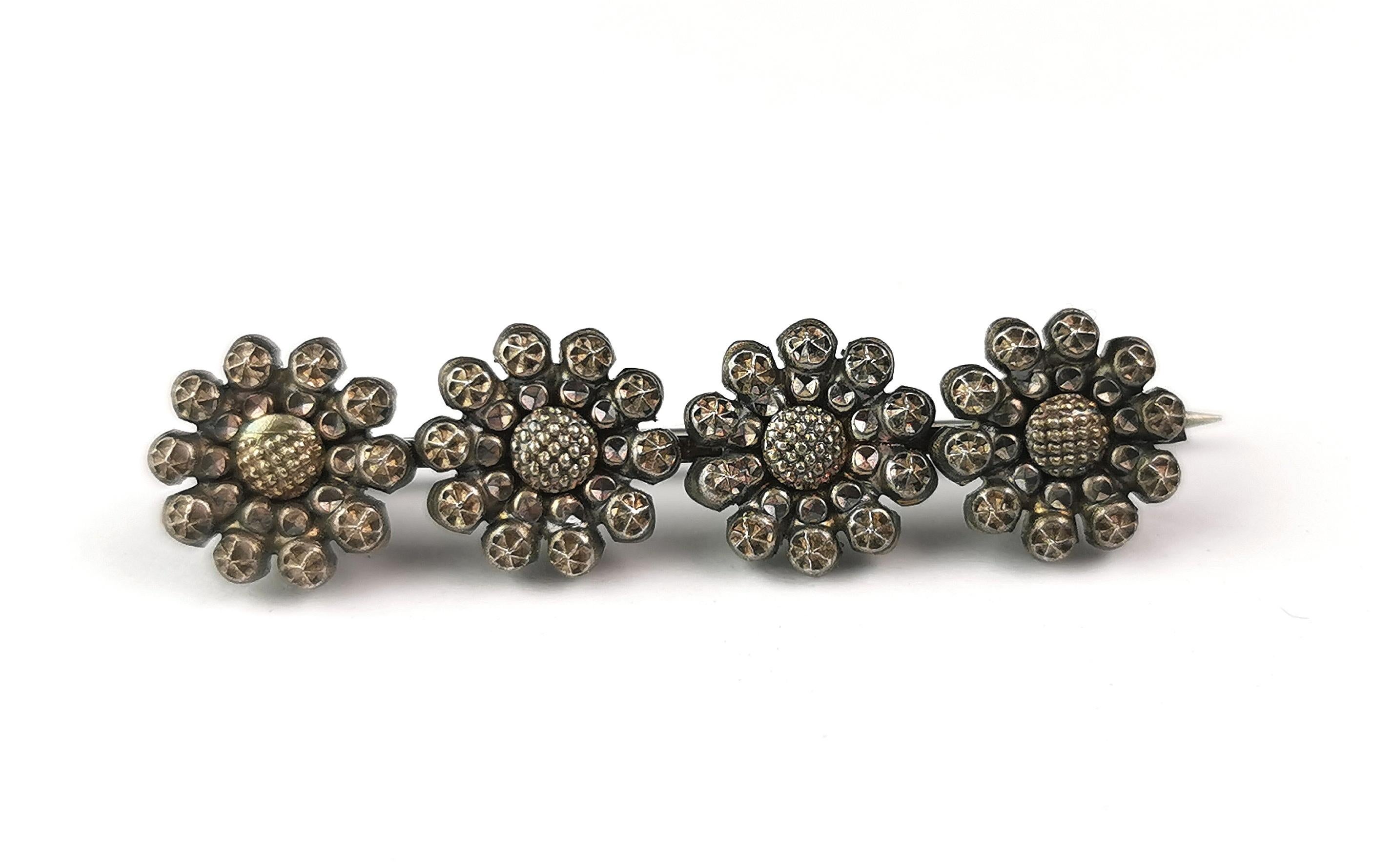 A sweet antique early Victorian era cut steel flower brooch.

It is a bar style brooch and could be used as a cravat or tie pin, it features a row of four individual cut steel flowers each with plenty of detail.

The flowers look like daisies.

It