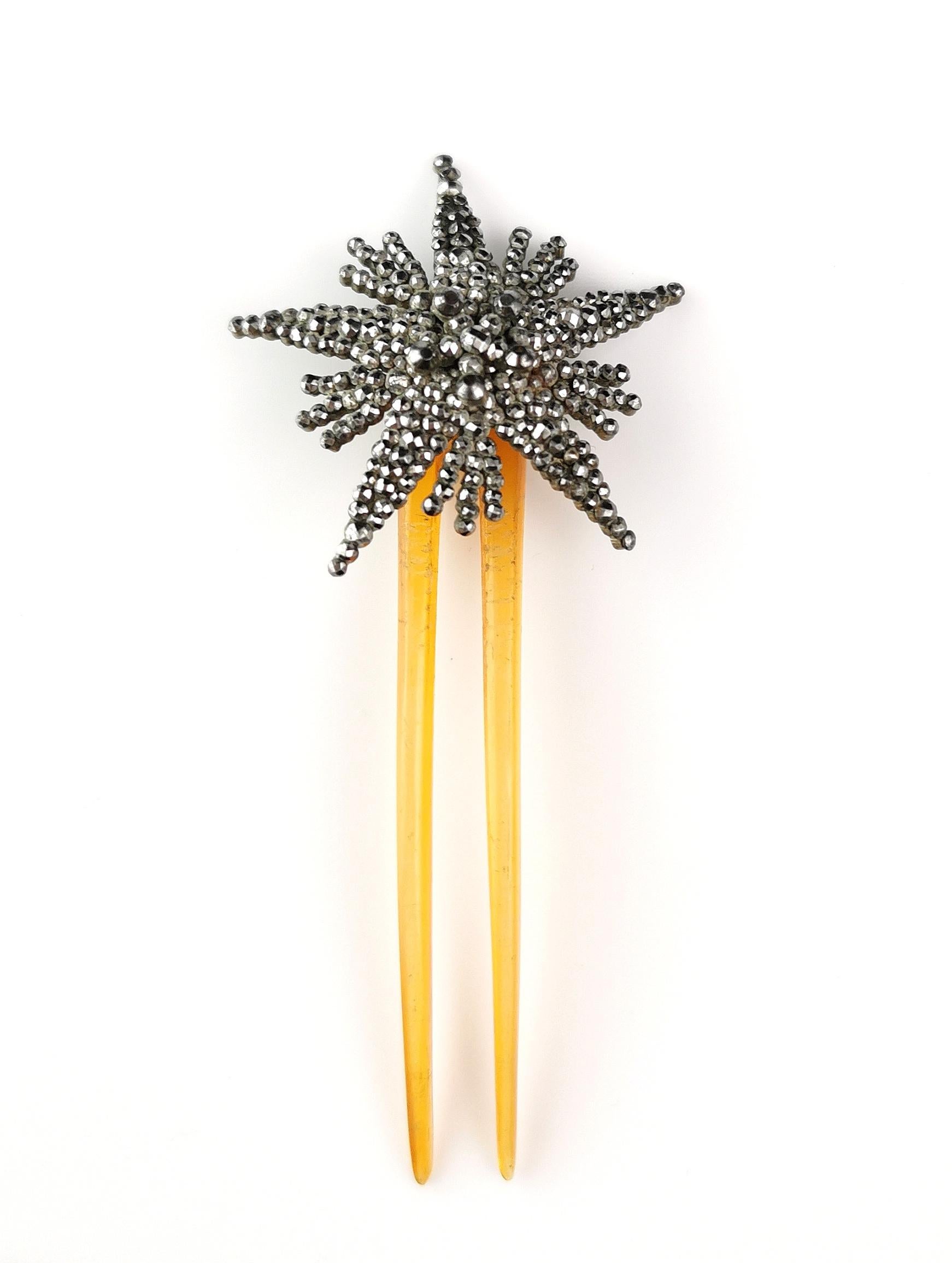 A gorgeous antique Victorian era hair comb.

It is a two pronged celluloid hair comb in an orange shade.

The top is adorned with a pretty cut steel star.

Cut steel was popularised in the 18th century, painstakingly hand cut and polished steel