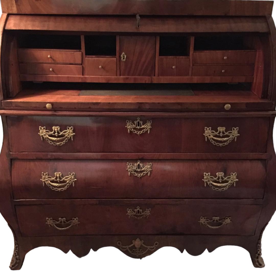 This antique cylinder front desk is a stunning piece of furniture that is sure to catch the eye of any antique lover.  A 1780’s dutch that features a unique bombe shape with a cylinder front opening over 3 drawers.  It has mahogany veneer over oak,