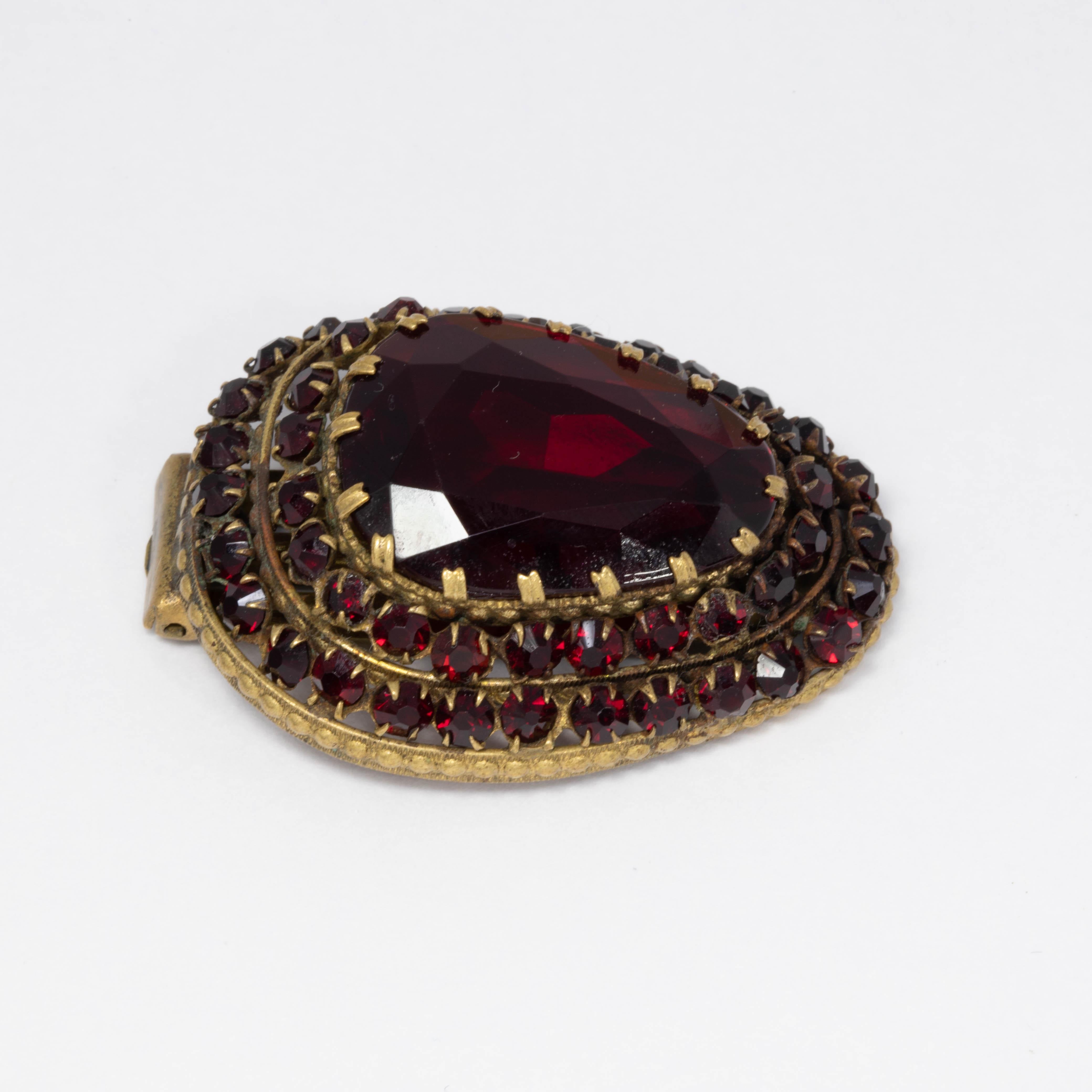 An extravagant Czechoslovakian clip, featuring a bold red centerpiece crystal accented with two rows of smaller jewels. Antique brass tone.

Signed Czechoslovakia