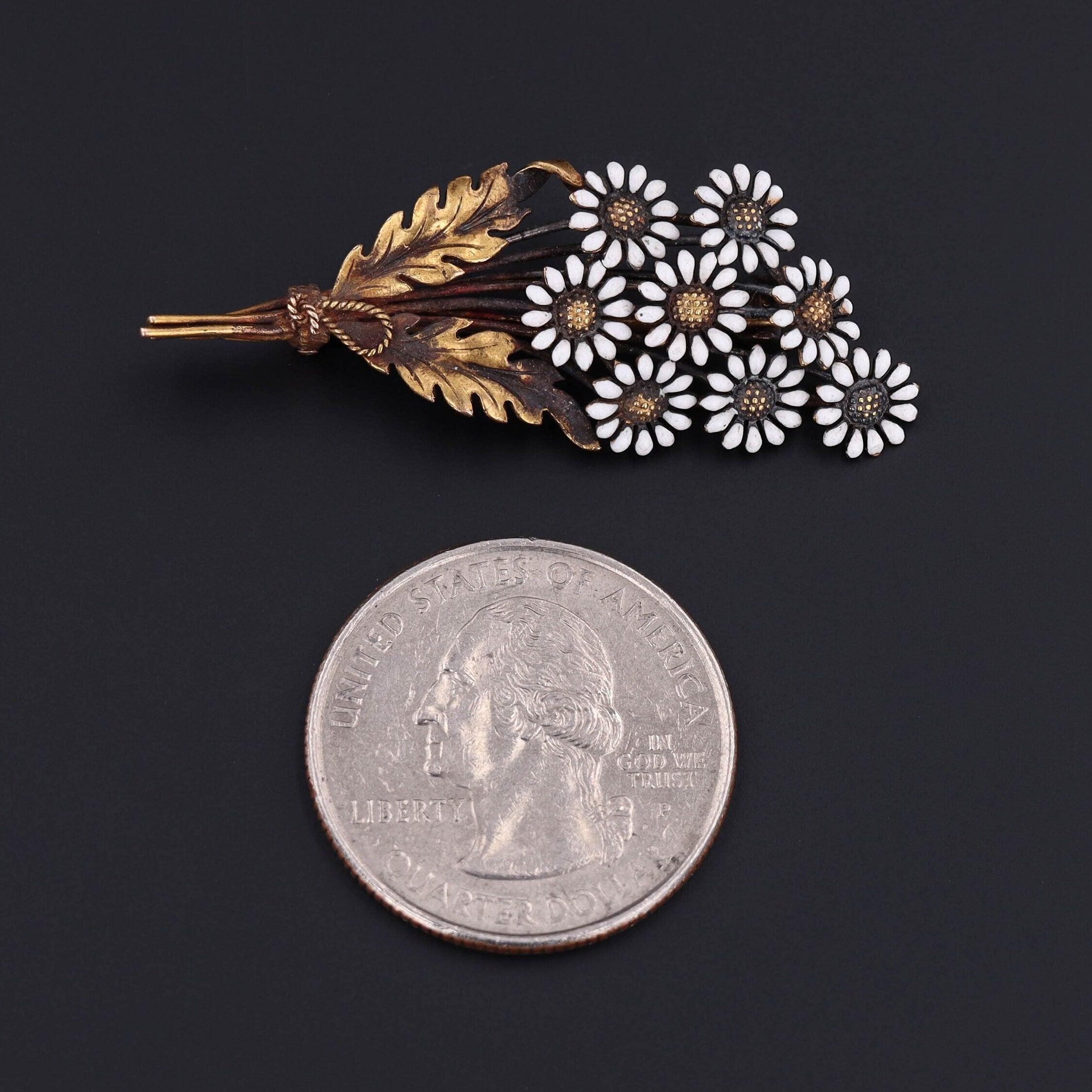 This antique brooch (circa 1910-1920) features a bouquet of 14k gold and white enamel daisies. The pin bears the makers mark for Carter Gough.

The piece measures 0.7 inches by 1.75 inches wide and is in very good condition.

The metal content of