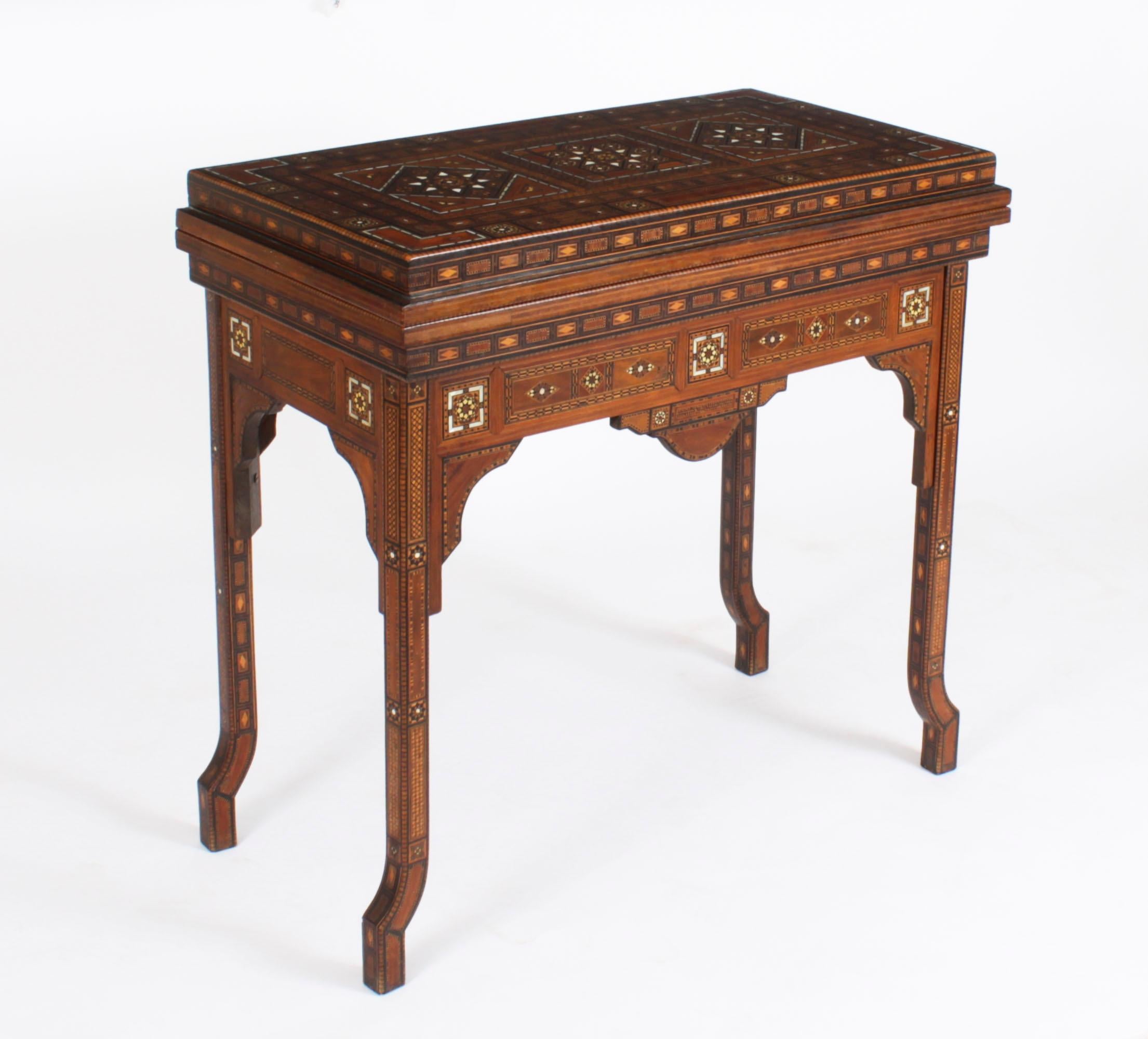 Dieser reichlich mit Intarsien versehene Spieltisch aus syrischem Damast stammt aus der Zeit um 1900 und hat  mehrfache geometrische und asymmetrische Intarsien aus verschiedenen Holzarten

Der Scharnierdeckel lässt sich öffnen und gibt den Blick