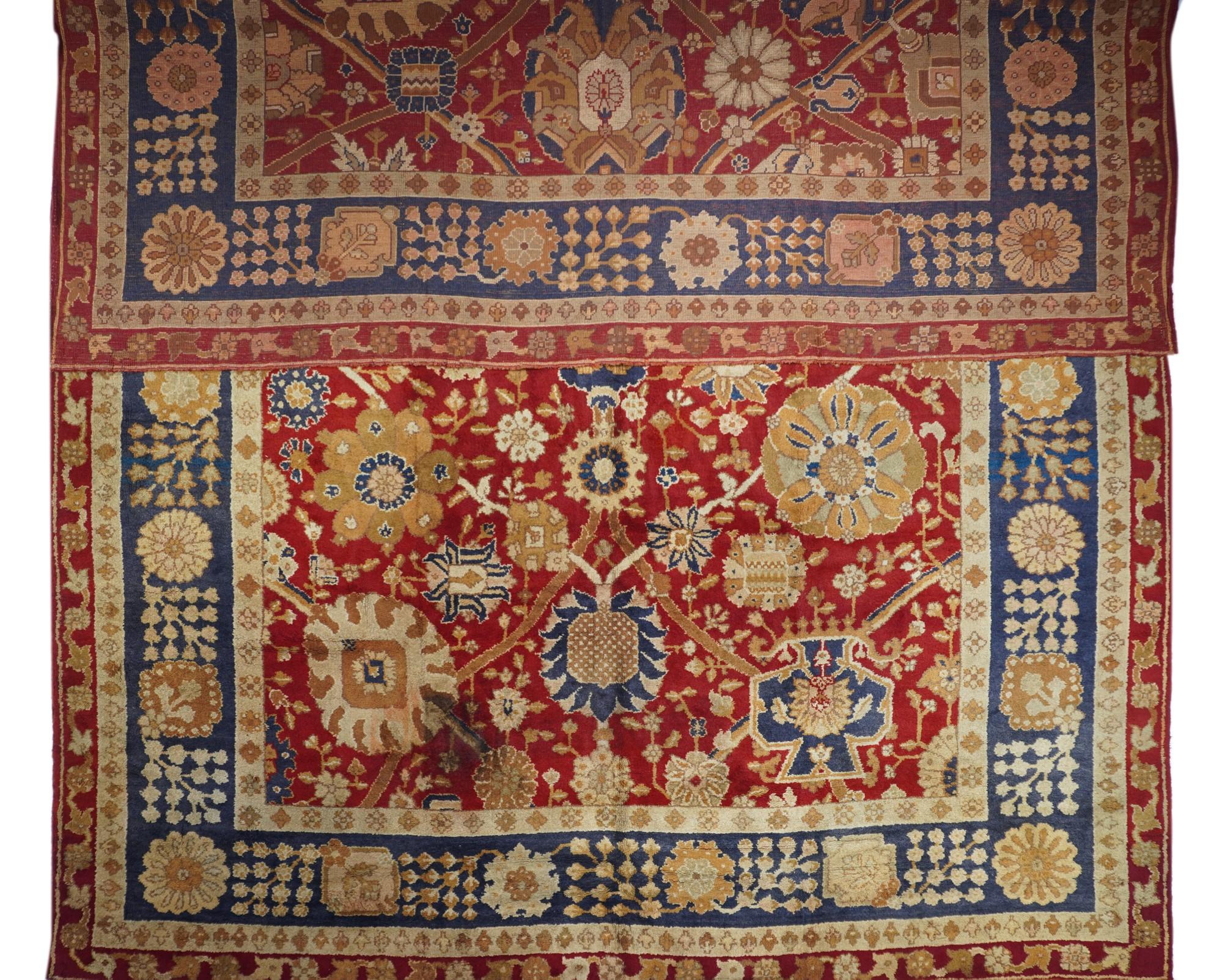 This is a particularly bold and well-rendered close-up of a 17th century “Vase carpet” design on a red field, with a vase, round, oval and petal palmettes, and a central navy escutcheon, tied together by a two level lozenge straight arabesqueries.