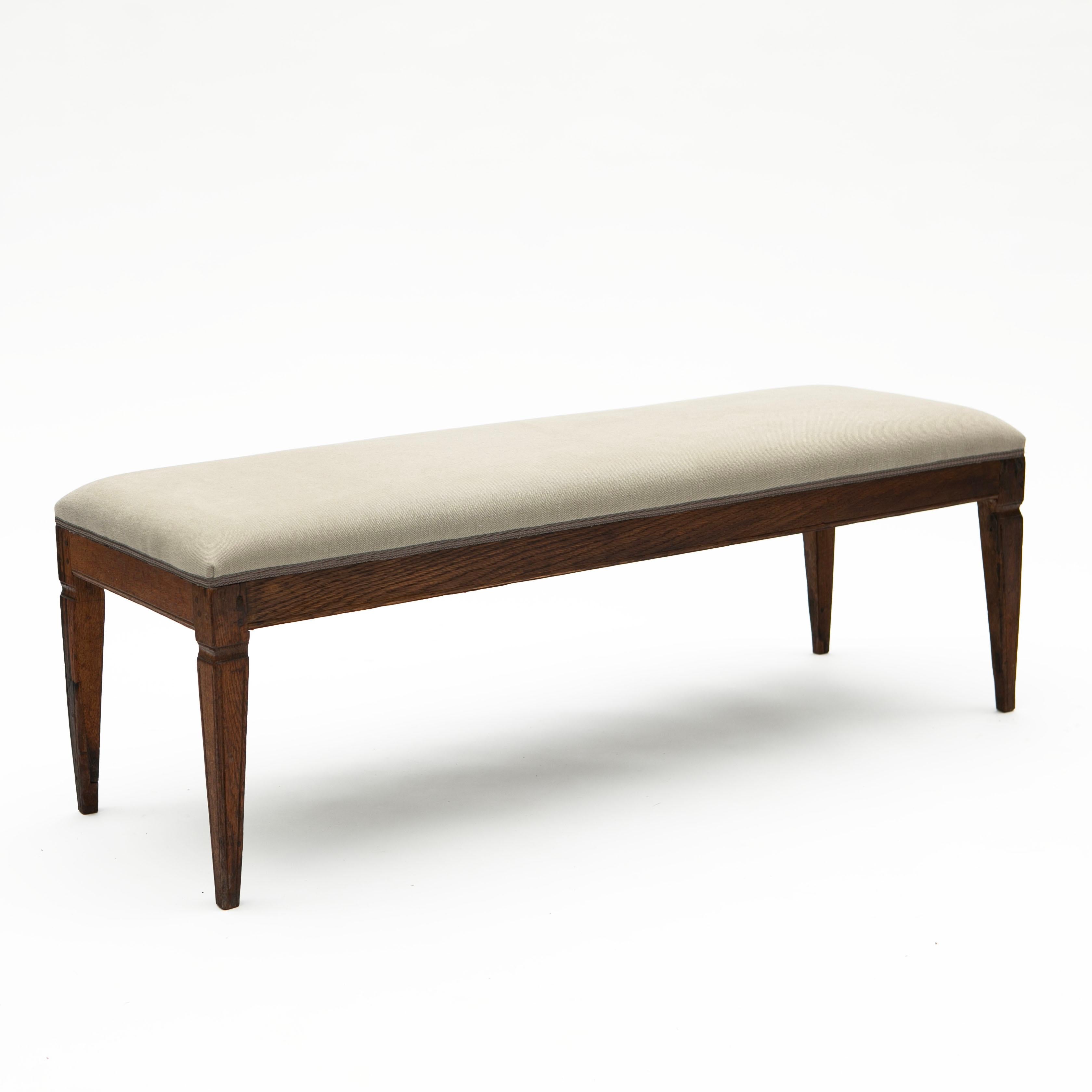 Louis XVI bench in oak, newly upholstered in light mist-gray linen.
Features apron with profiled edge resting on tapered legs.

Originating from Denmark, 1780-1800