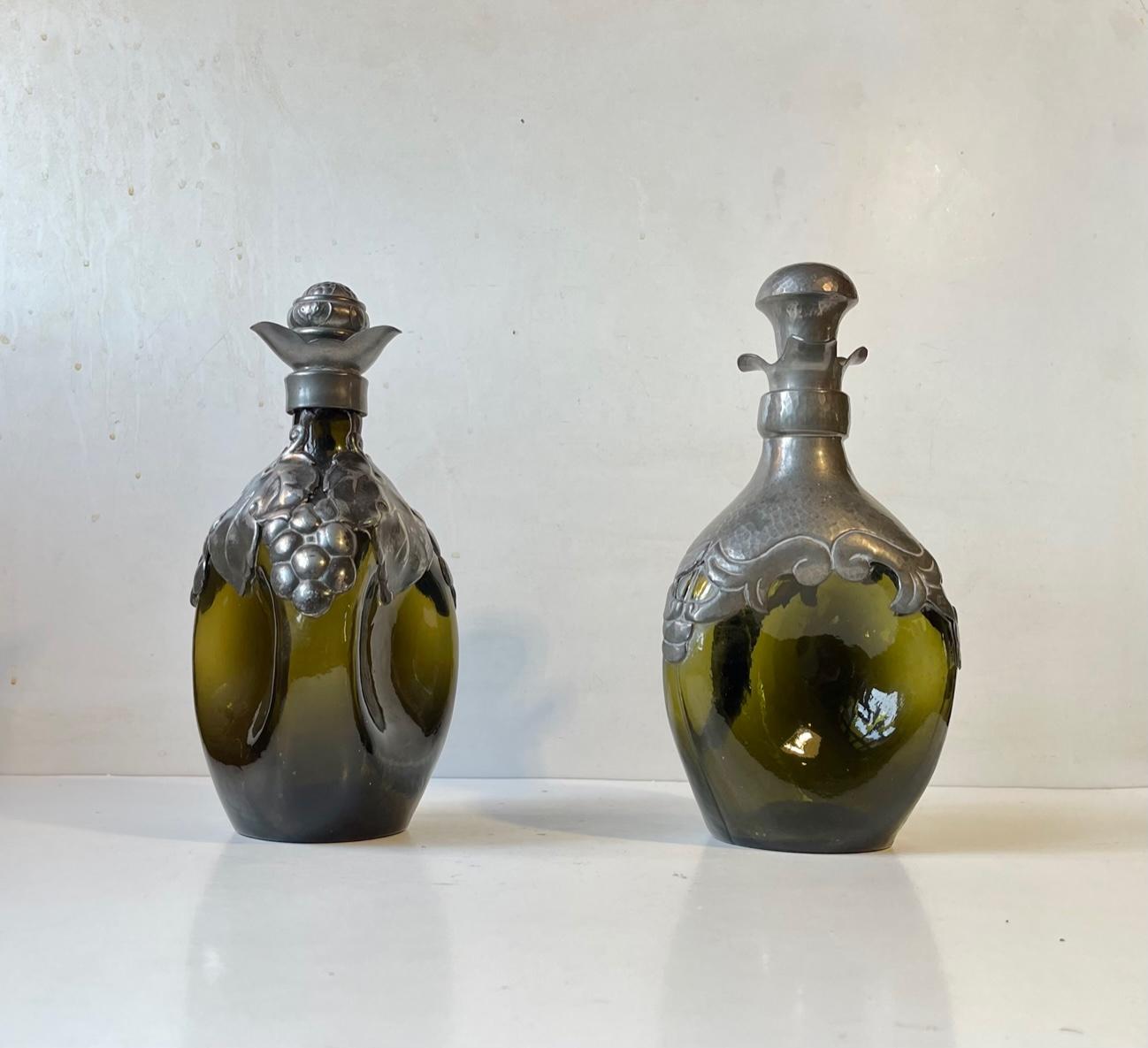 Et set of triangular decanters in green glass. Decorated with hand-set/crafted pewter mounts. Original stoppers in pewter and cork. Distinct Danish Skønvirke style the equivalent of art nouveau/Jugend/Arts and Crafts. Very reminiscent of Thorvald