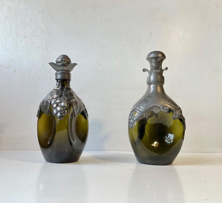 Et set of triangular decanters in green glass. Decorated with hand-set/crafted pewter mounts. Original stoppers in pewter and cork. Distinct Danish Skønvirke style the equivalent of art nouveau/Jugend/Arts and Crafts. Very reminiscent of Thorvald