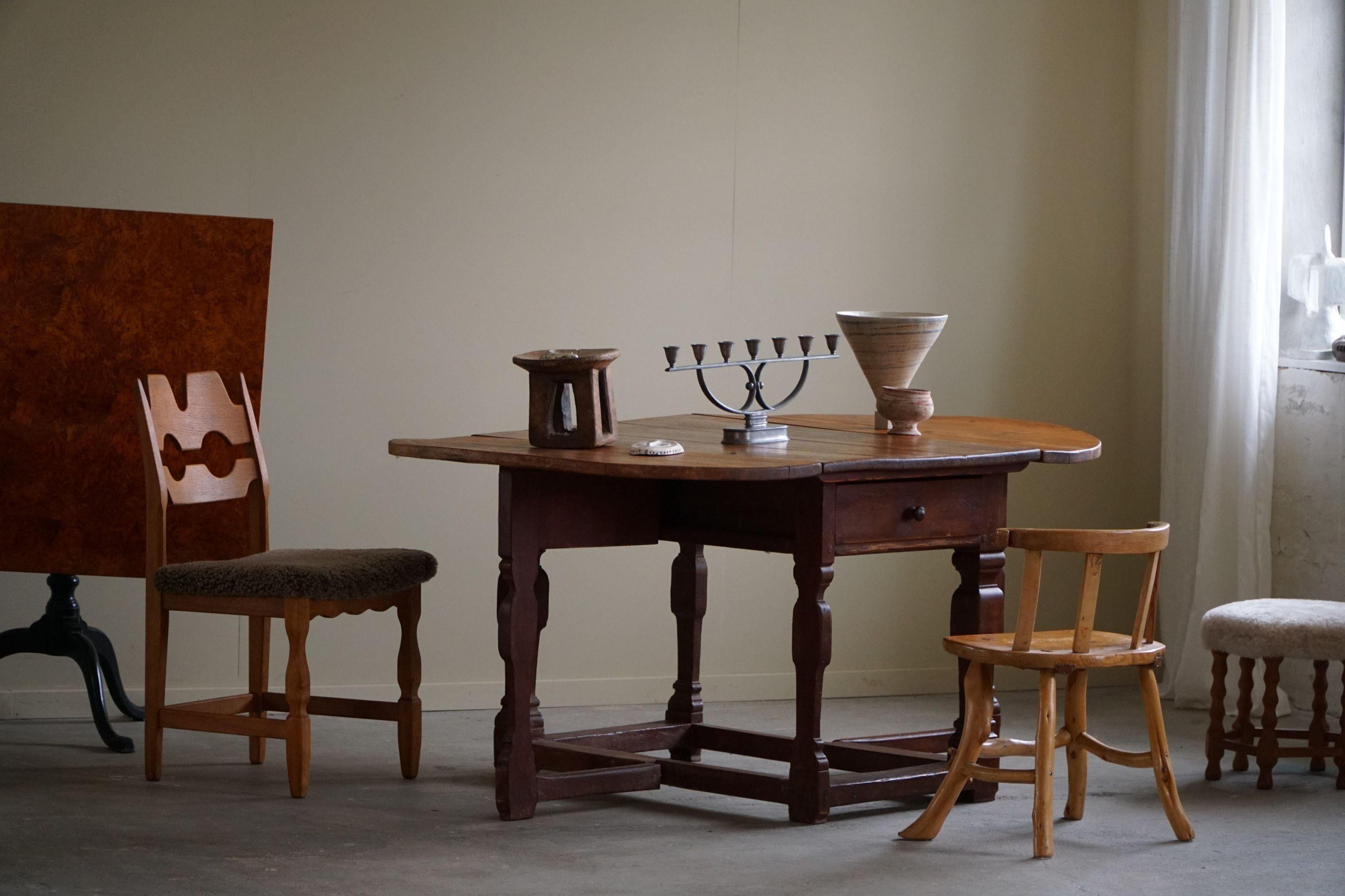 Dieser antike dänische Barocktisch mit hängenden Flügeln aus dem 18. Jahrhundert ist ein charmantes Stück Geschichte. Er ist aus massivem Kiefernholz gefertigt und zeigt die rustikale Schönheit des Holzes mit seinen warmen Tönen und natürlichen