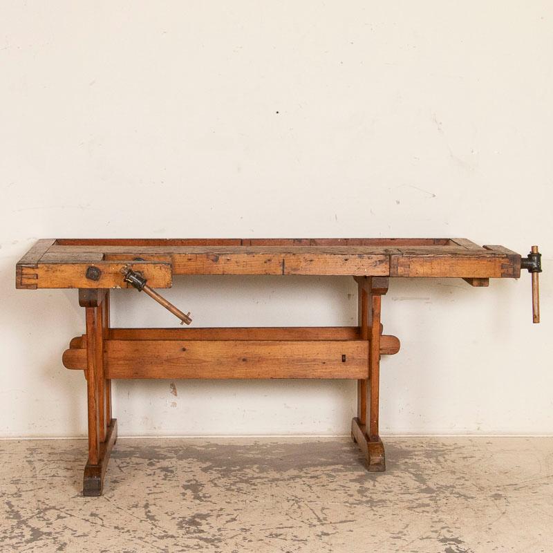 This vintage carpenters' workbench has a warm patina after years of traditional use. The scratches, dings and even touches of spilled paint add to the character of this 6' work table. It has two wrought-iron vices with wood handles and a recessed