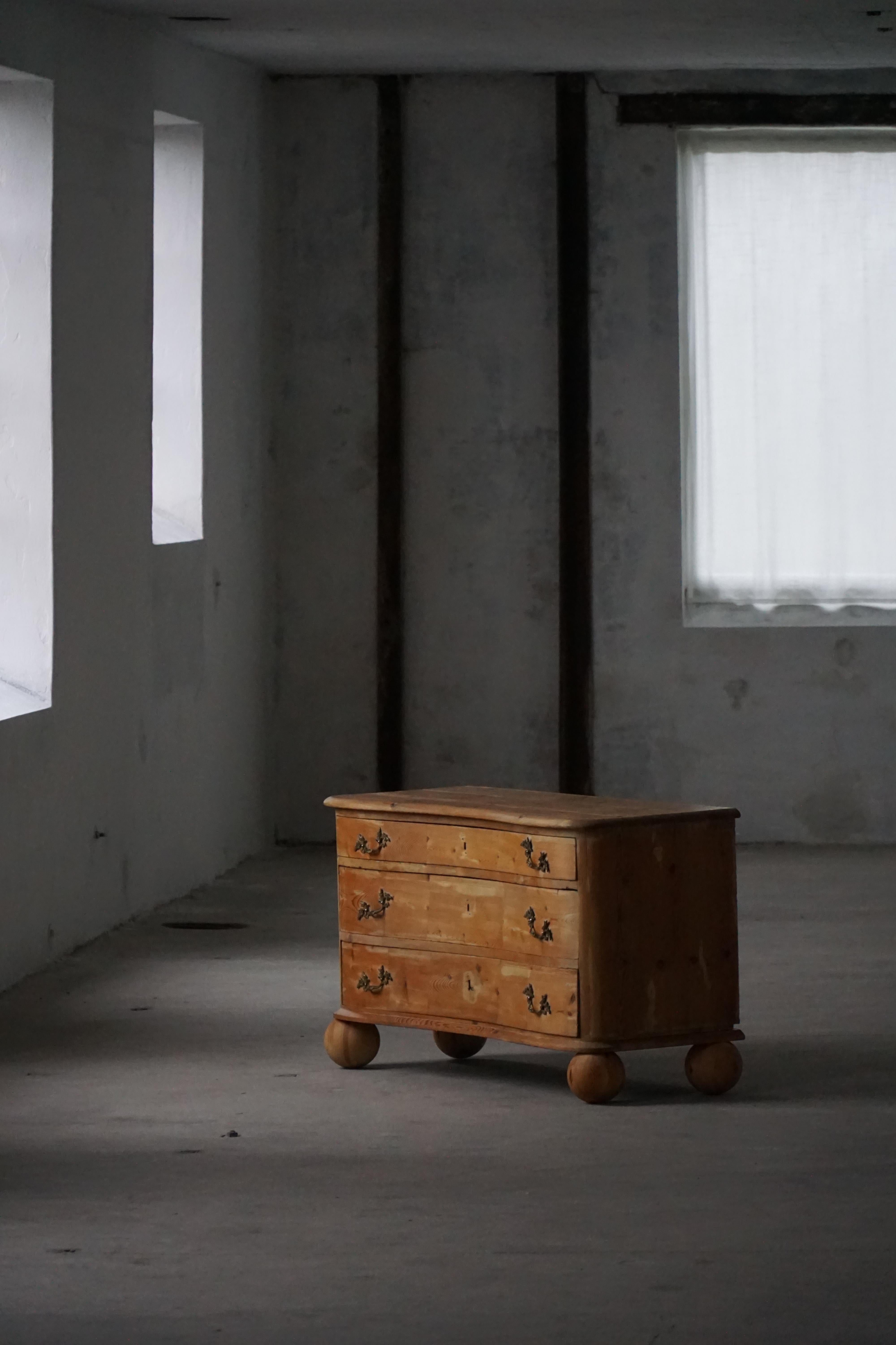 A charming antique chest of drawers crafted in solid pine, featuring a gently curved front and beautifully aged surface with a warm, natural tone. Made by a Danish Cabinetmaker in the late 19th Century. The piece presents three spacious drawers,