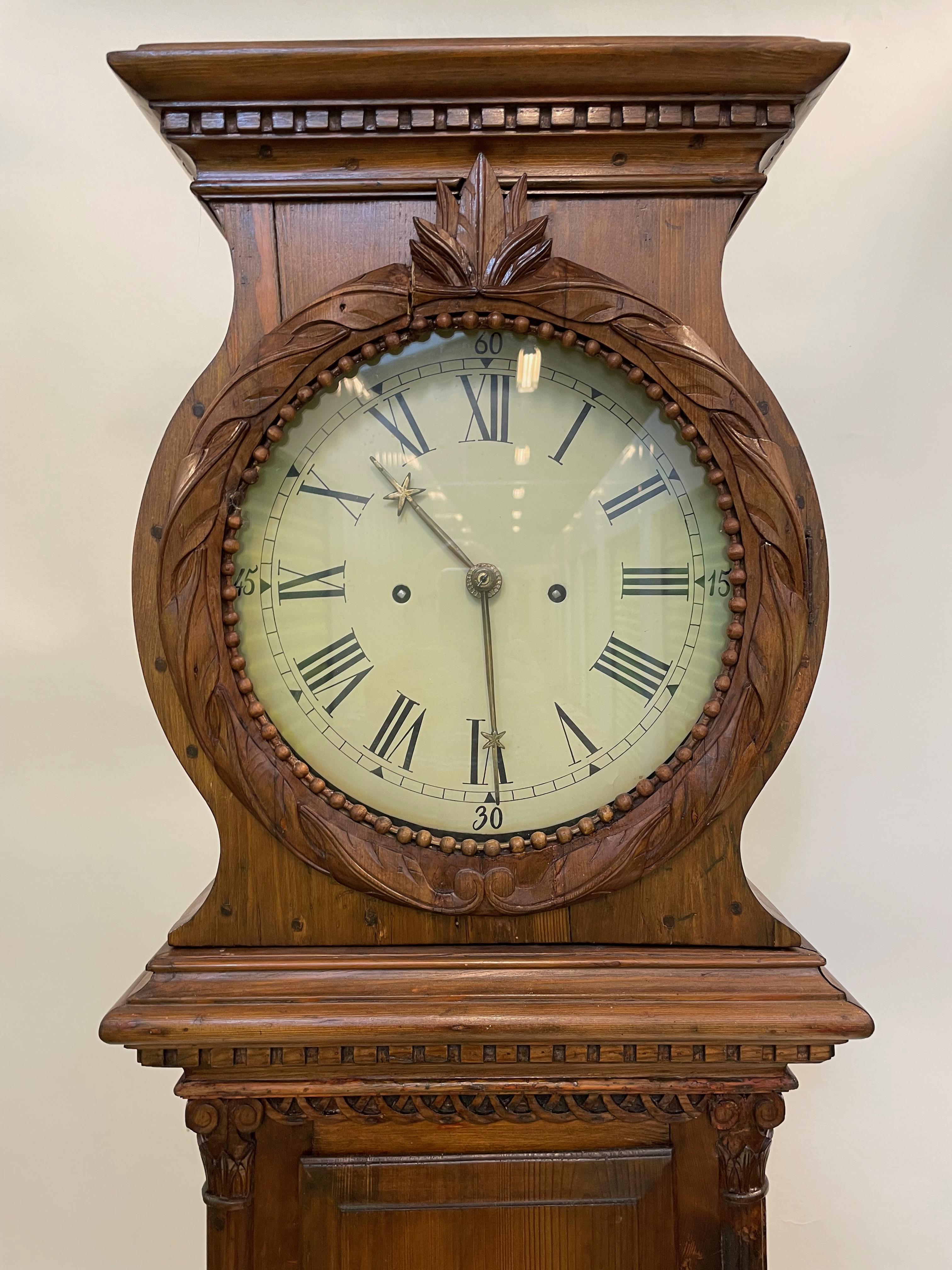 This stately Grandfather clock is from the first quarter of the 19th century. It is made in the traditional Scandinavian style of clock making and has charming and whimsical details on the face of the clock as well as filigreed wooden side access